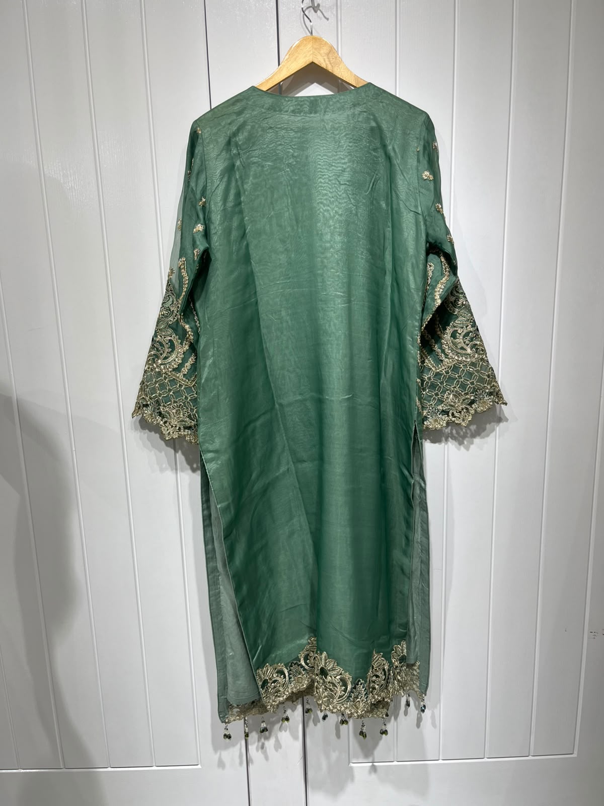 A green ensemble with ornate gold-toned embroidery, statement cuffs and a matching motif-patterned dupatta.
