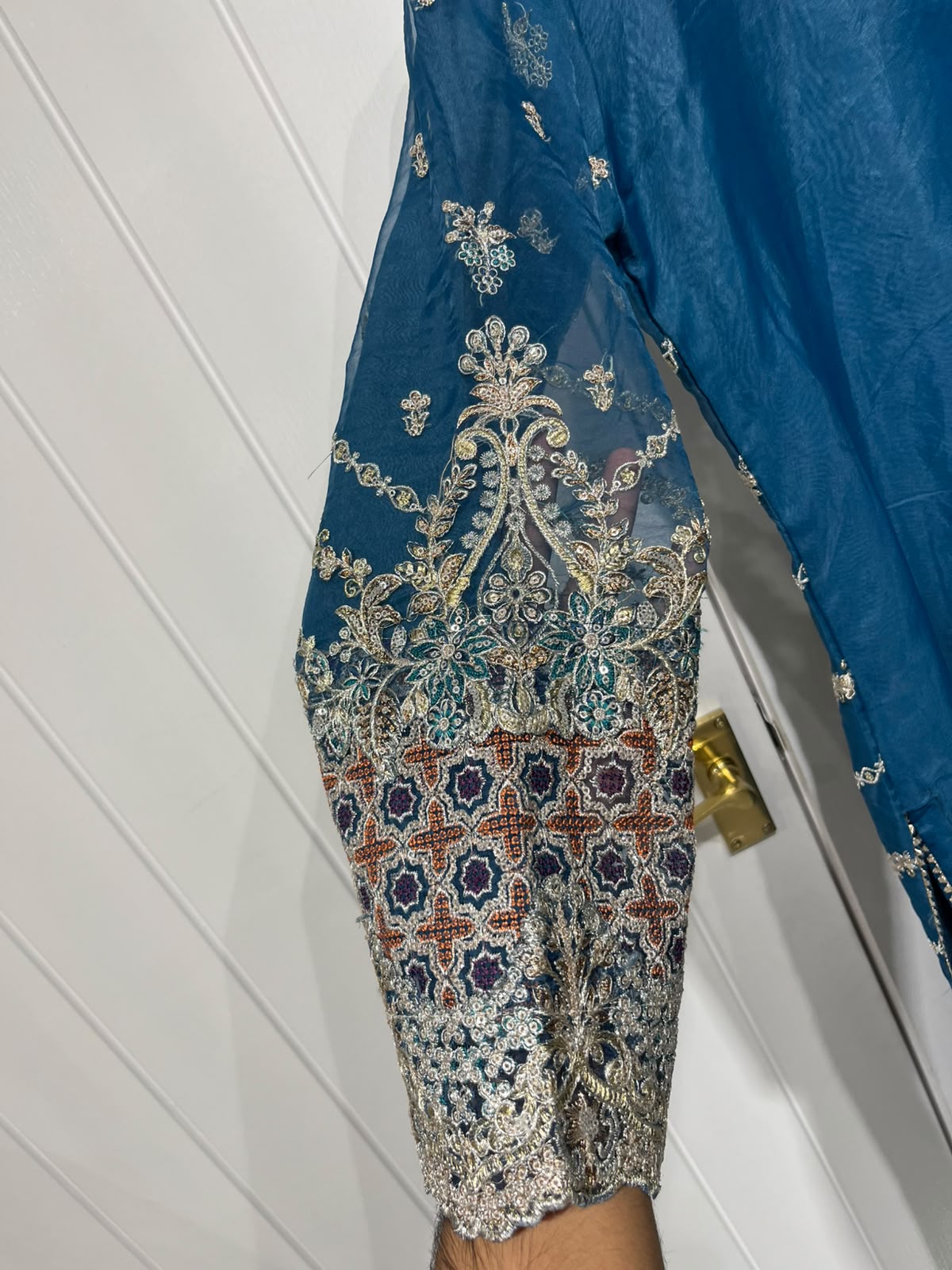 A teal blue ensemble with an ornate embroidered neckline, floral…