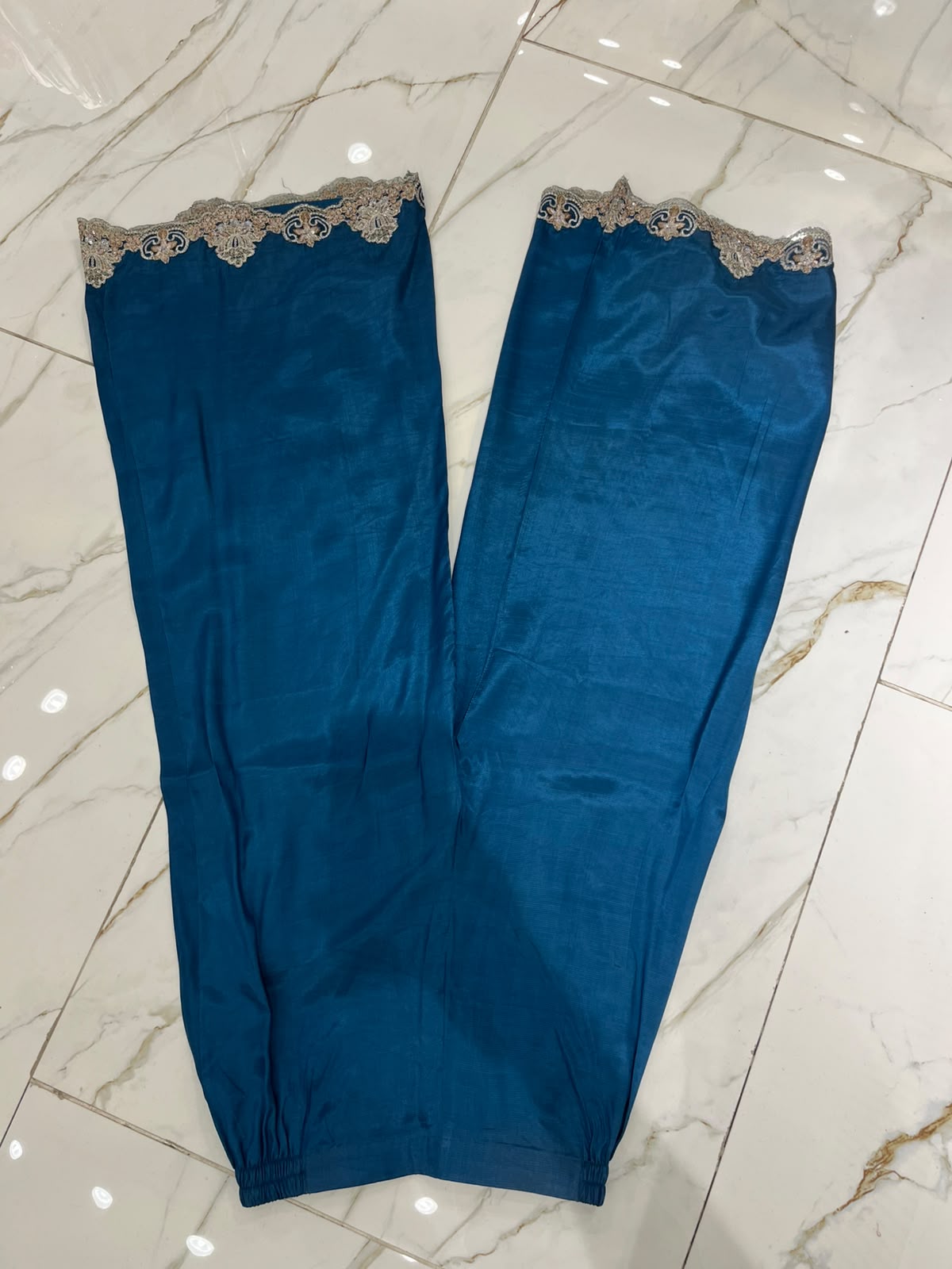 A teal blue ensemble with an ornate embroidered neckline, floral…