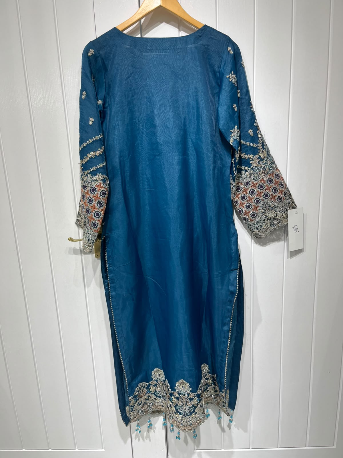 A teal blue ensemble with an ornate embroidered neckline, floral…