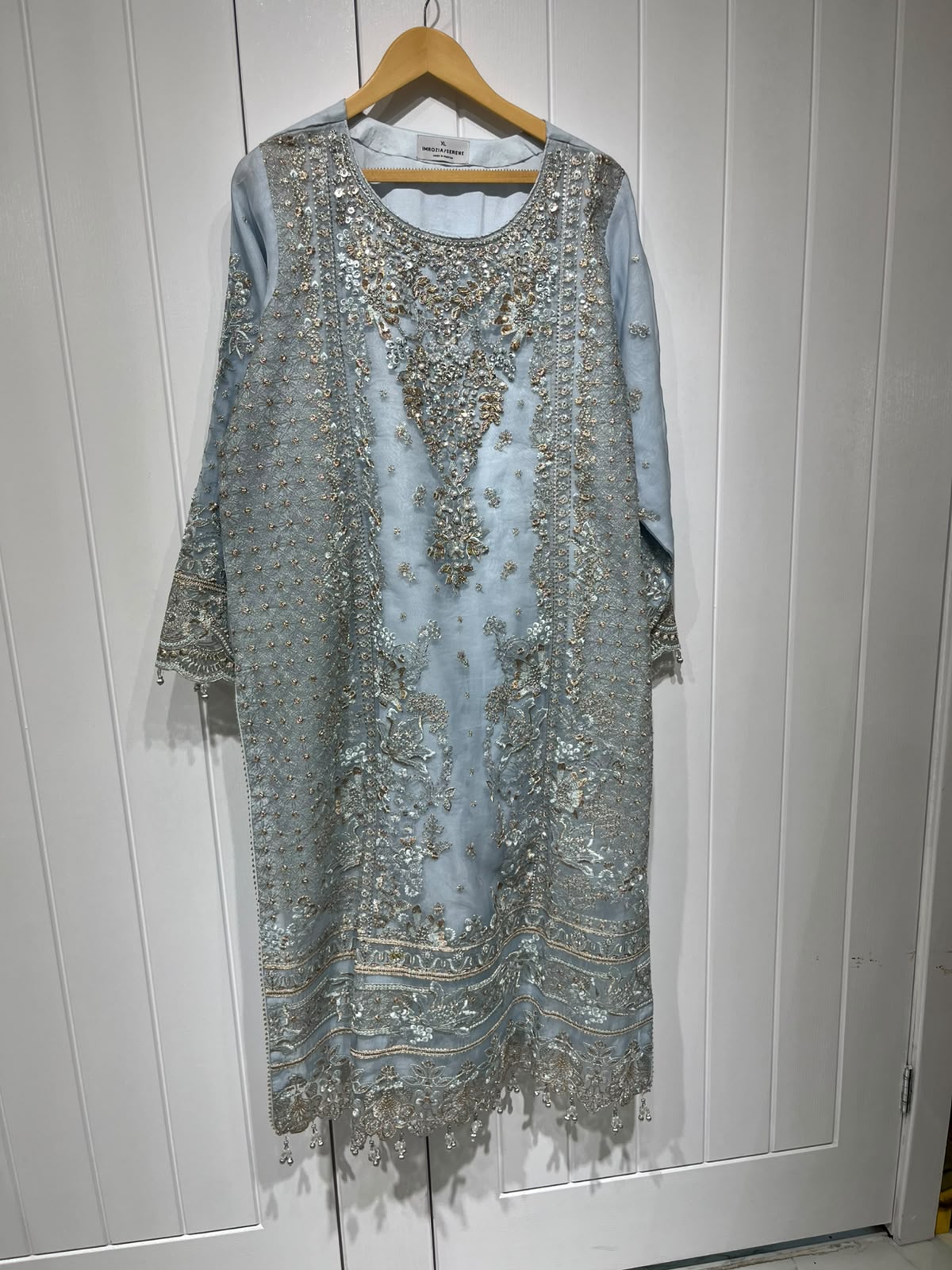 An ice blue ensemble with intricate metallic-toned embroidery, ornate…