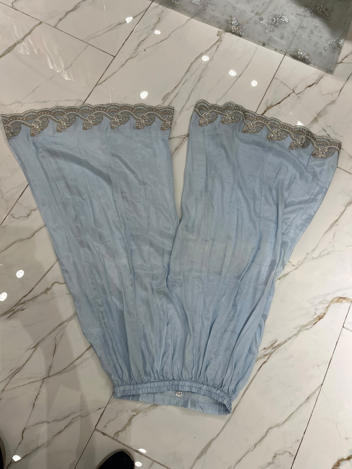 An ice blue ensemble with intricate metallic-toned embroidery, ornate…
