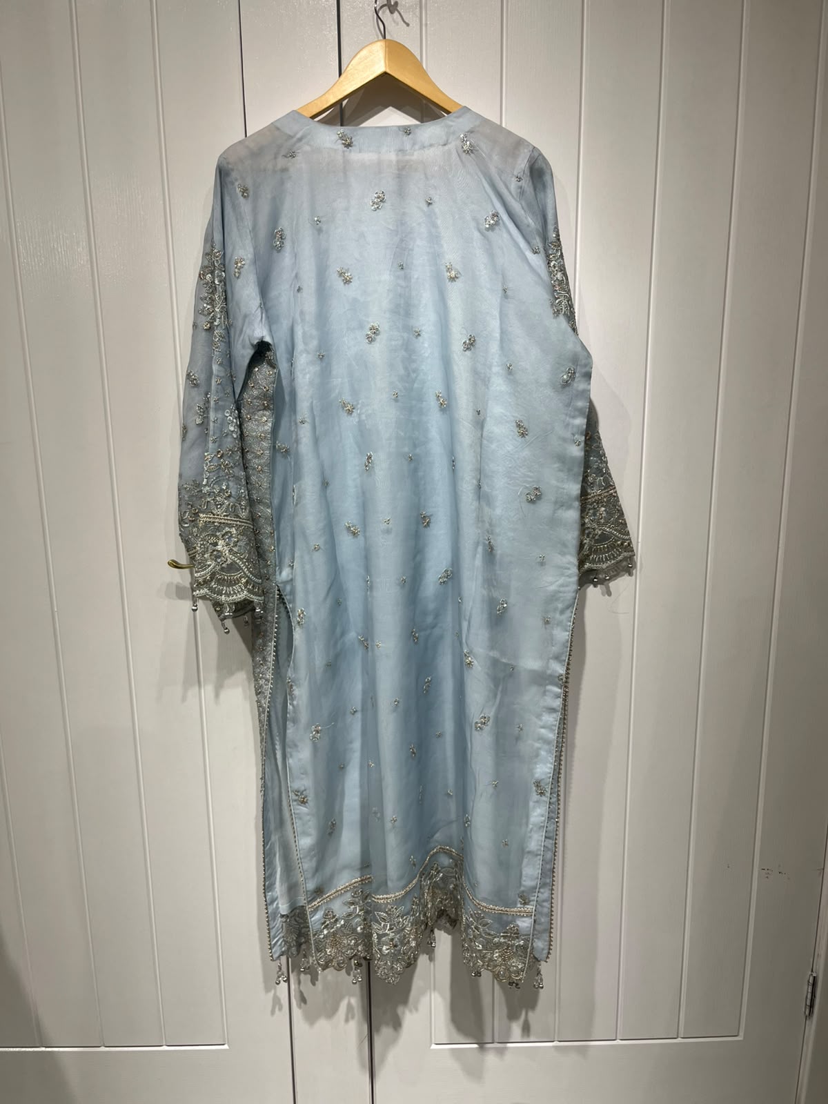 An ice blue ensemble with intricate metallic-toned embroidery, ornate…