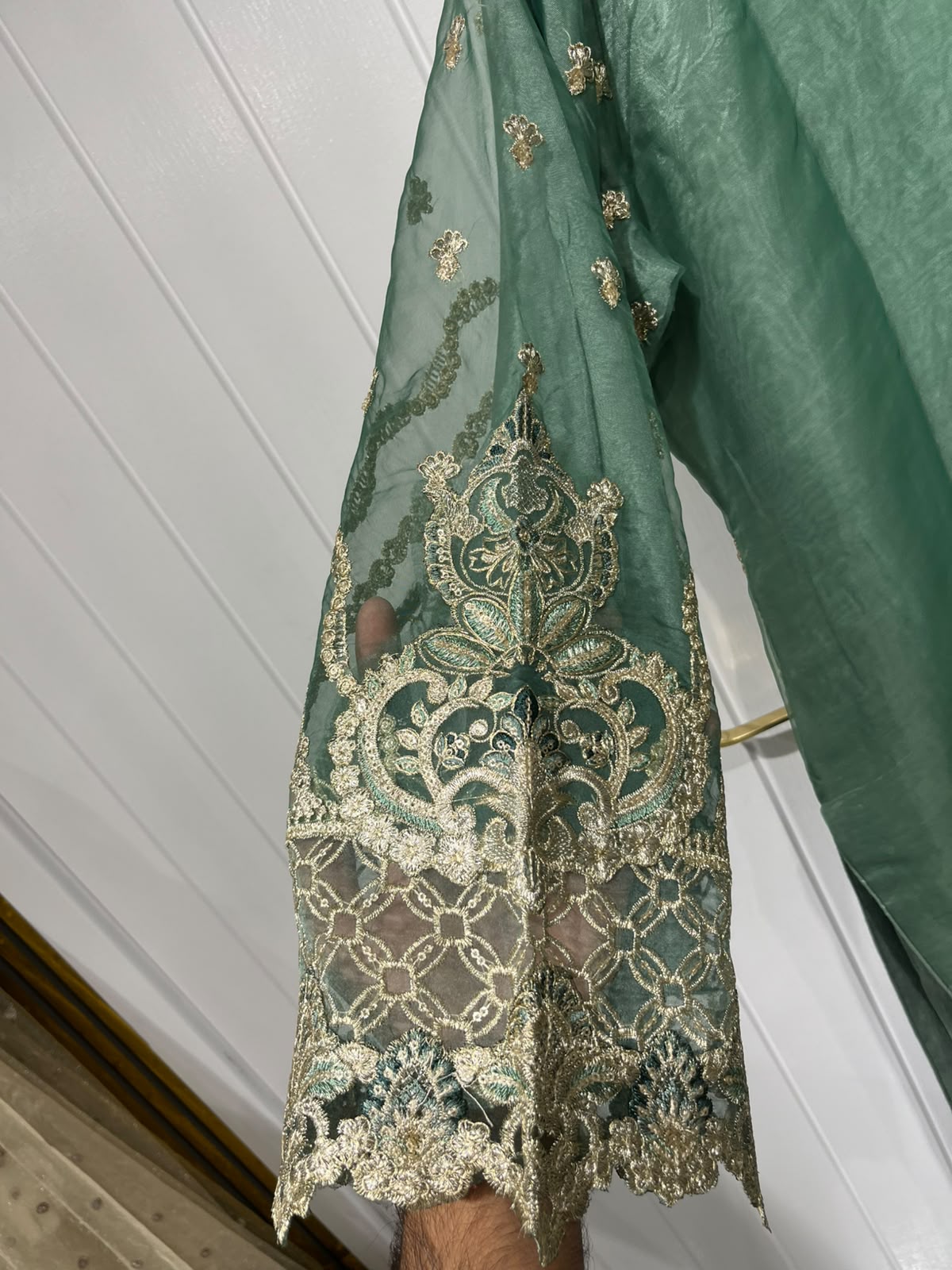 A green ensemble with ornate gold-toned embroidery, statement cuffs…
