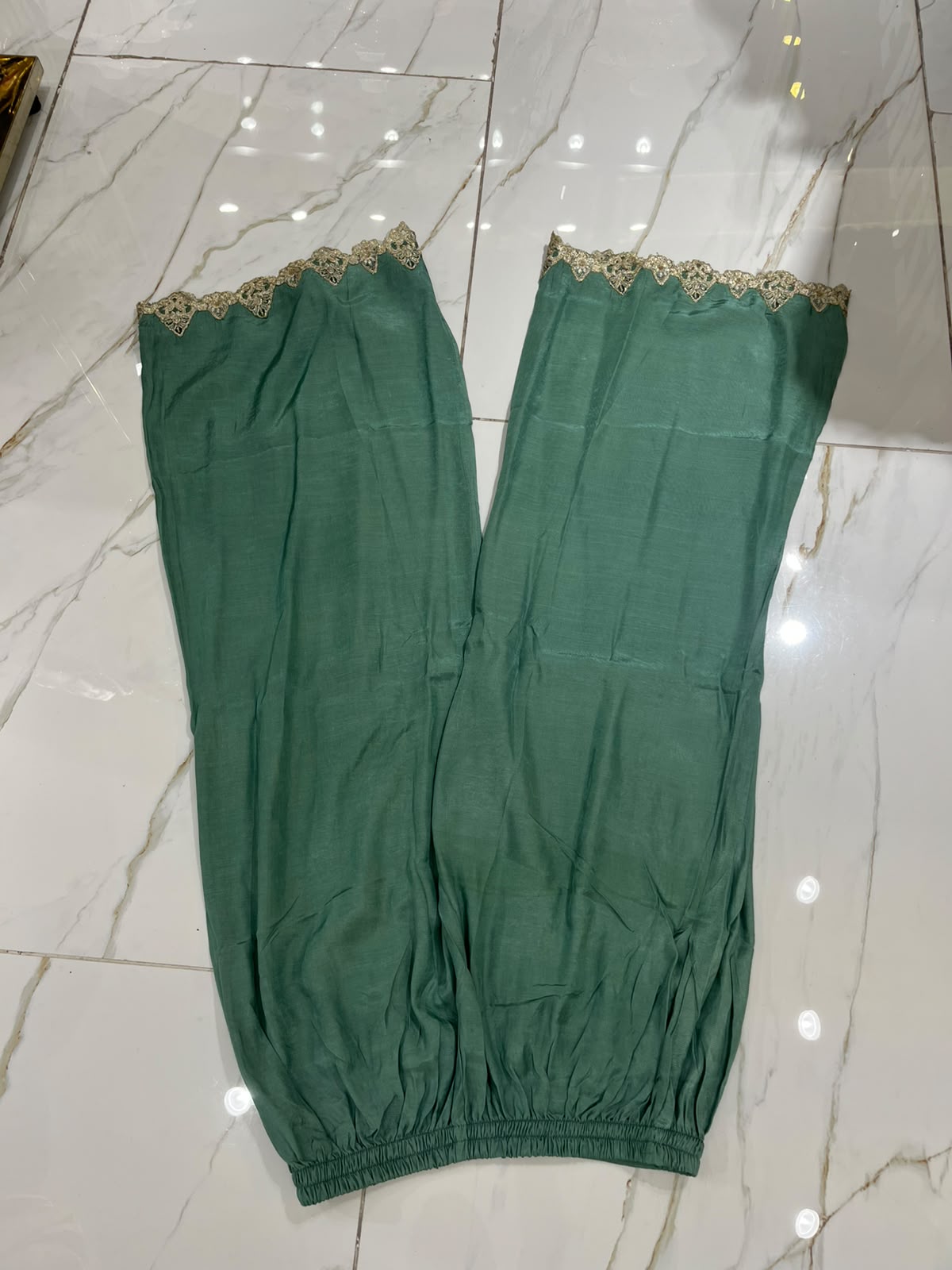 A green ensemble with ornate gold-toned embroidery, statement cuffs…