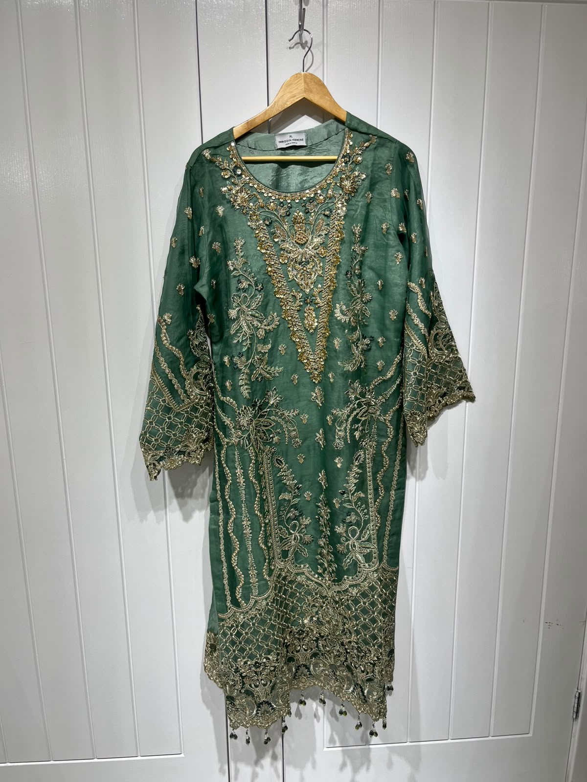 A green ensemble with ornate gold-toned embroidery, statement cuffs…