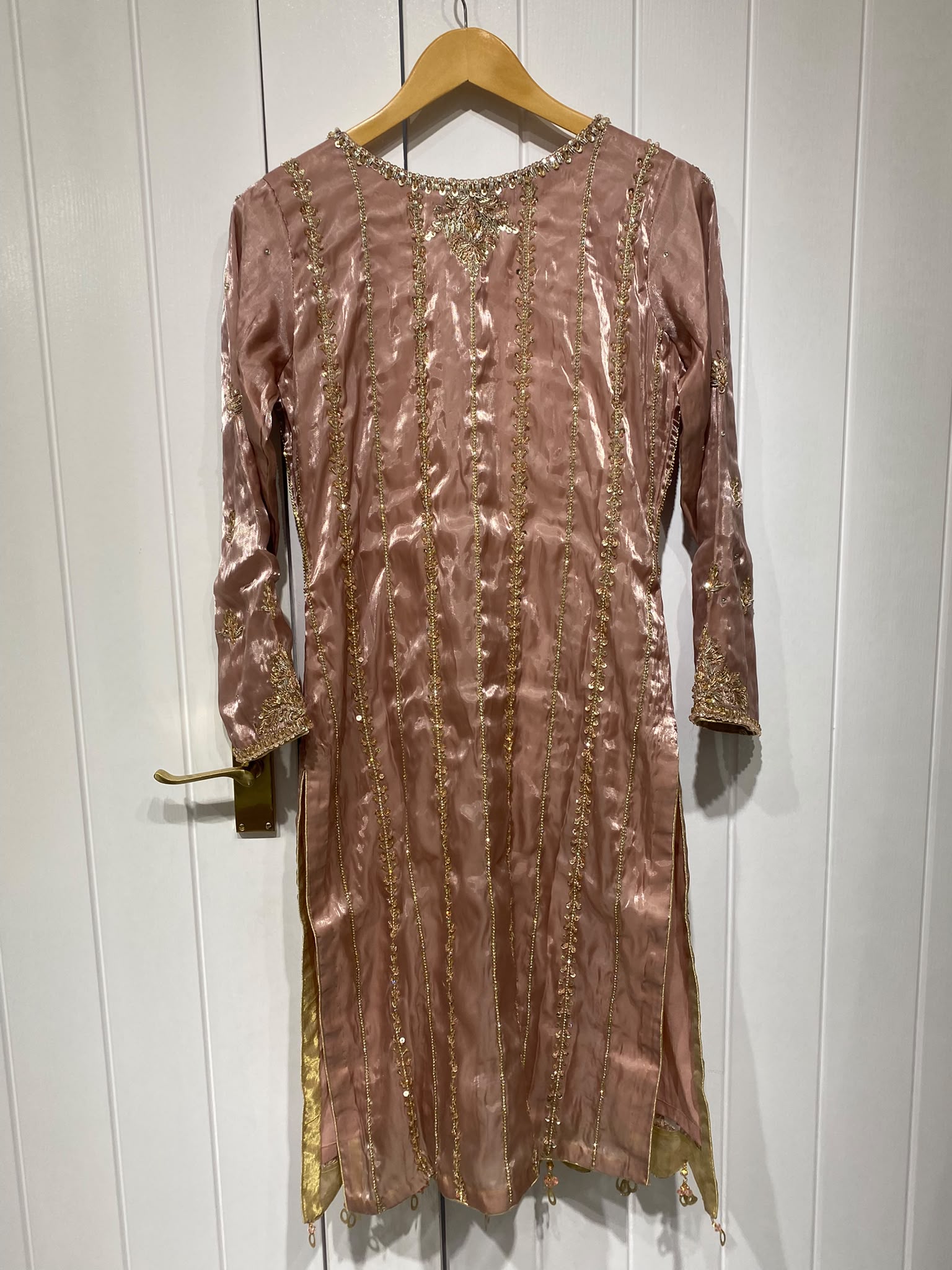 A dusty rose ensemble with a richly embroidered front, decorated…