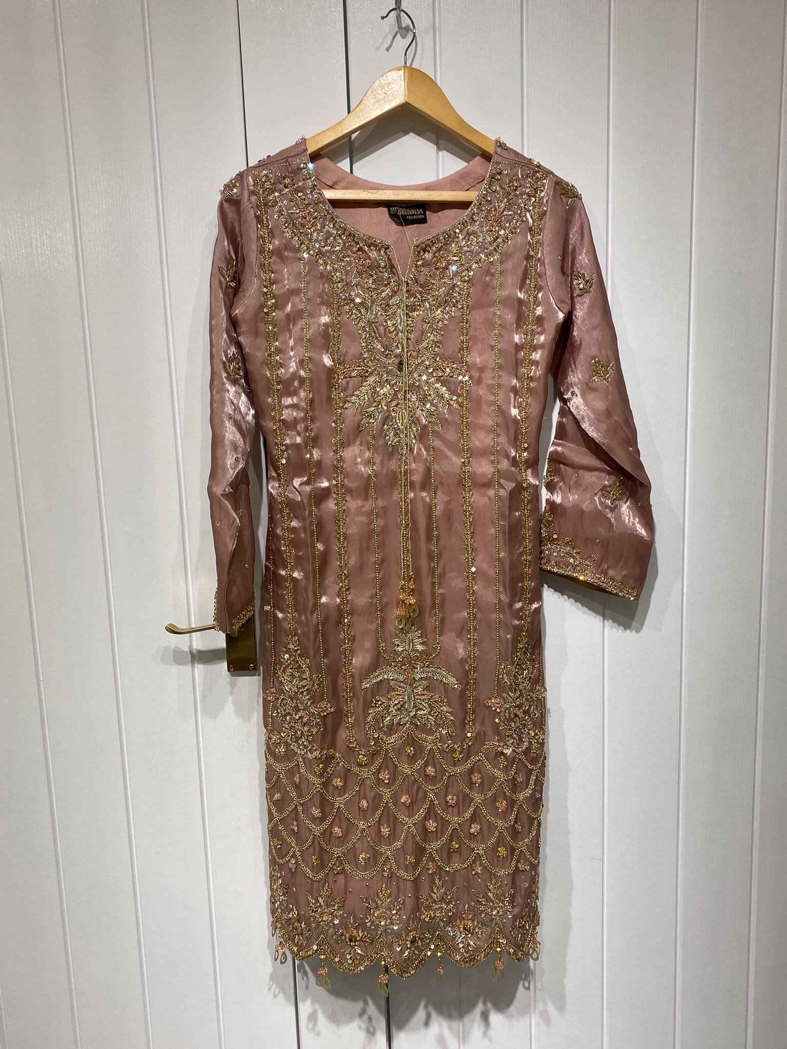 A dusty rose ensemble with a richly embroidered front, decorated…