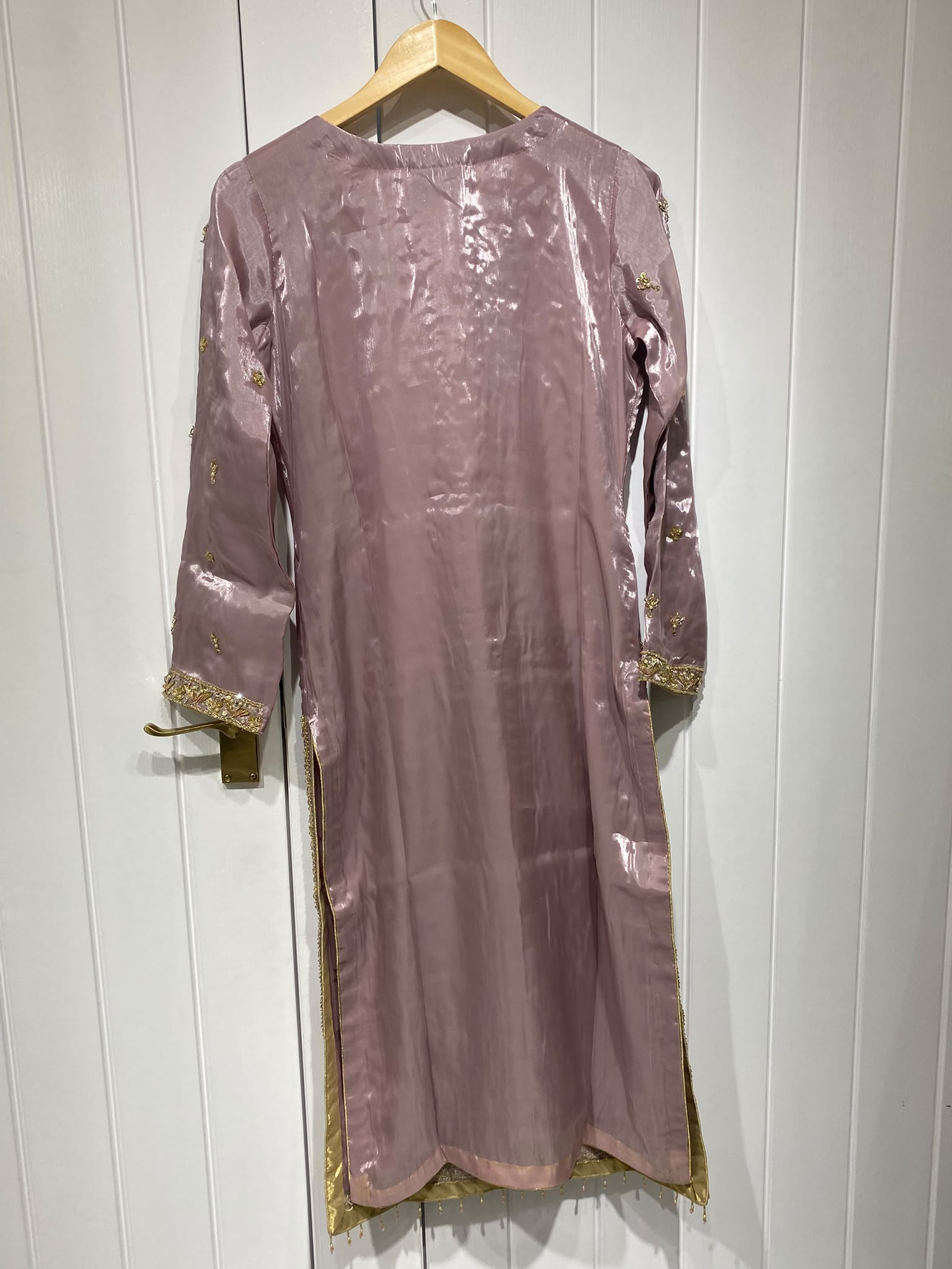 A dusty mauve ensemble with a long gold-toned neckline, vertical…