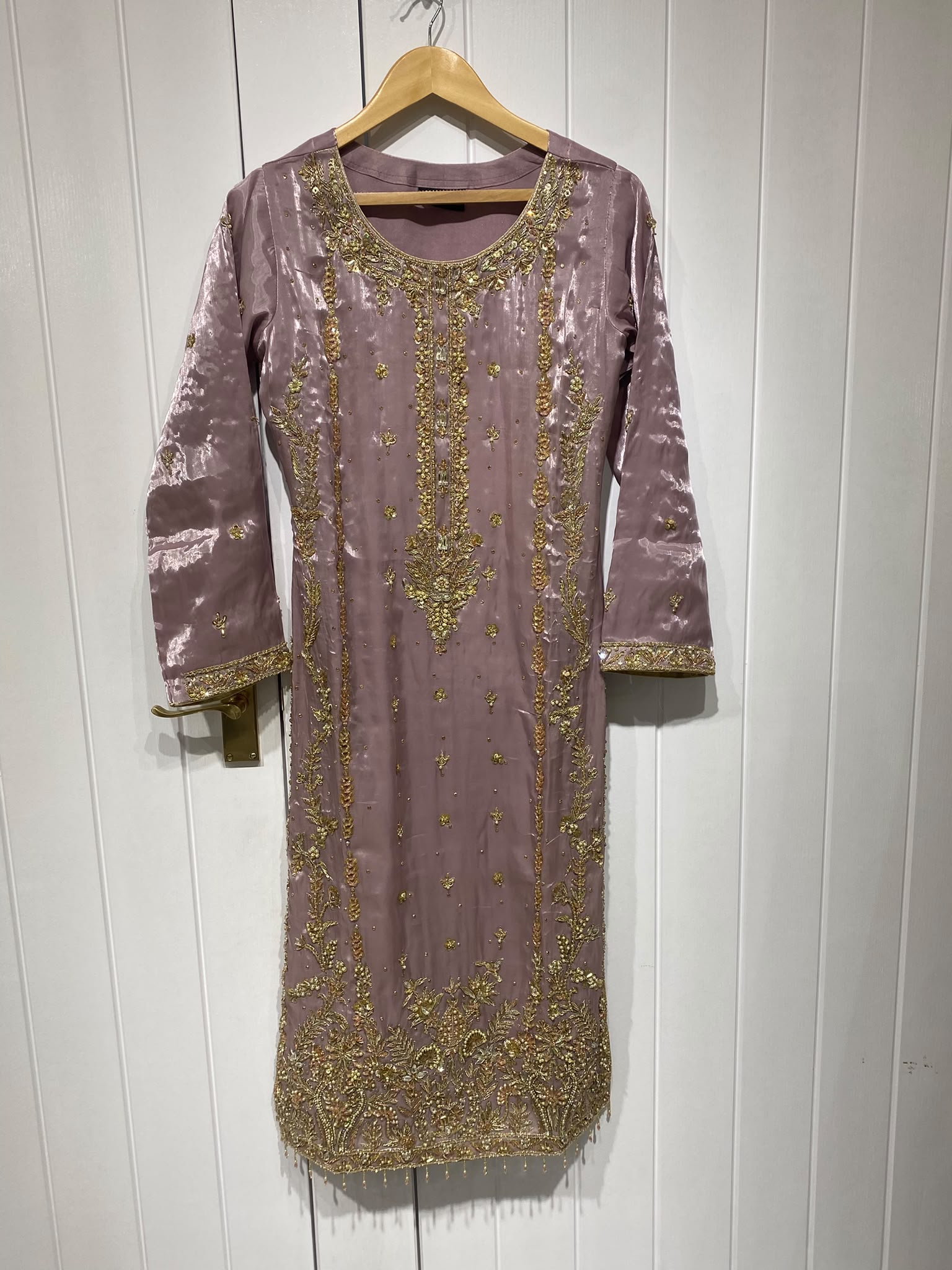 A dusty mauve ensemble with a long gold-toned neckline, vertical…