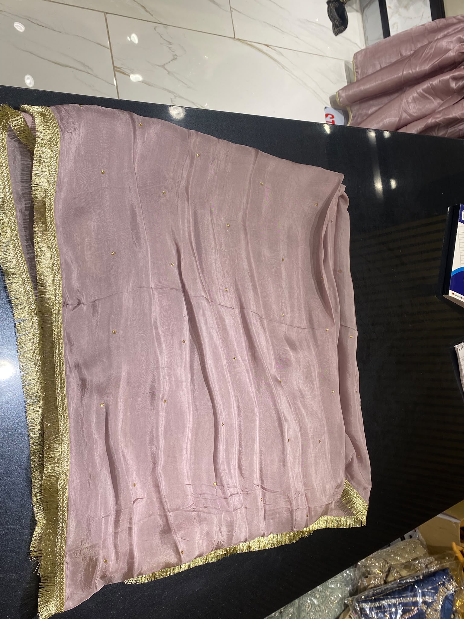 A dusty mauve ensemble with a long gold-toned neckline, vertical…