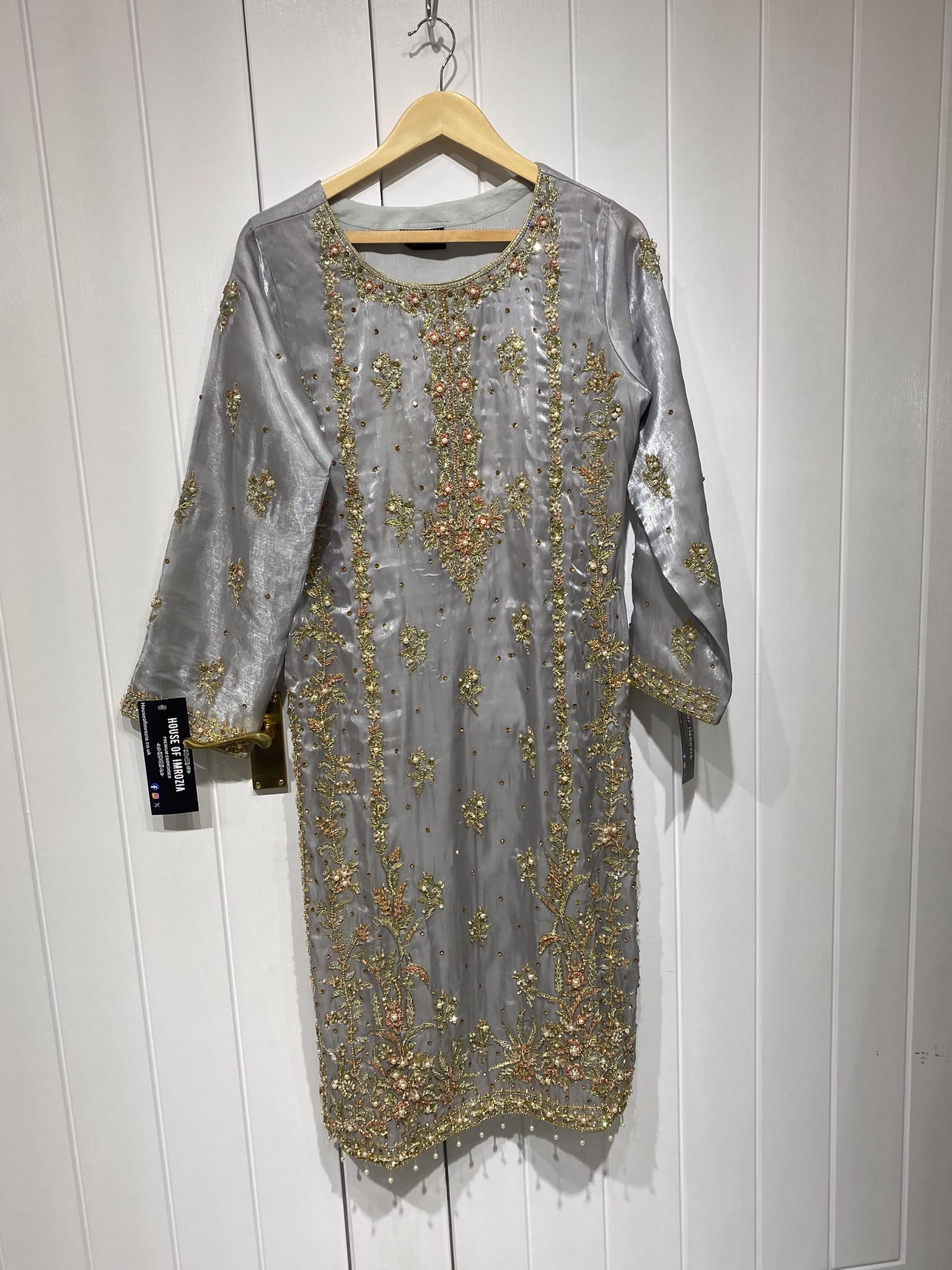 A silver grey ensemble with ornate gold-toned embroidery, decorated…
