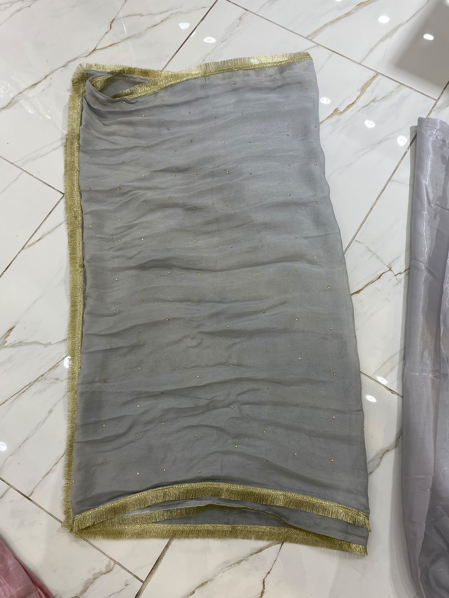 A silver grey ensemble with ornate gold-toned embroidery, decorated…