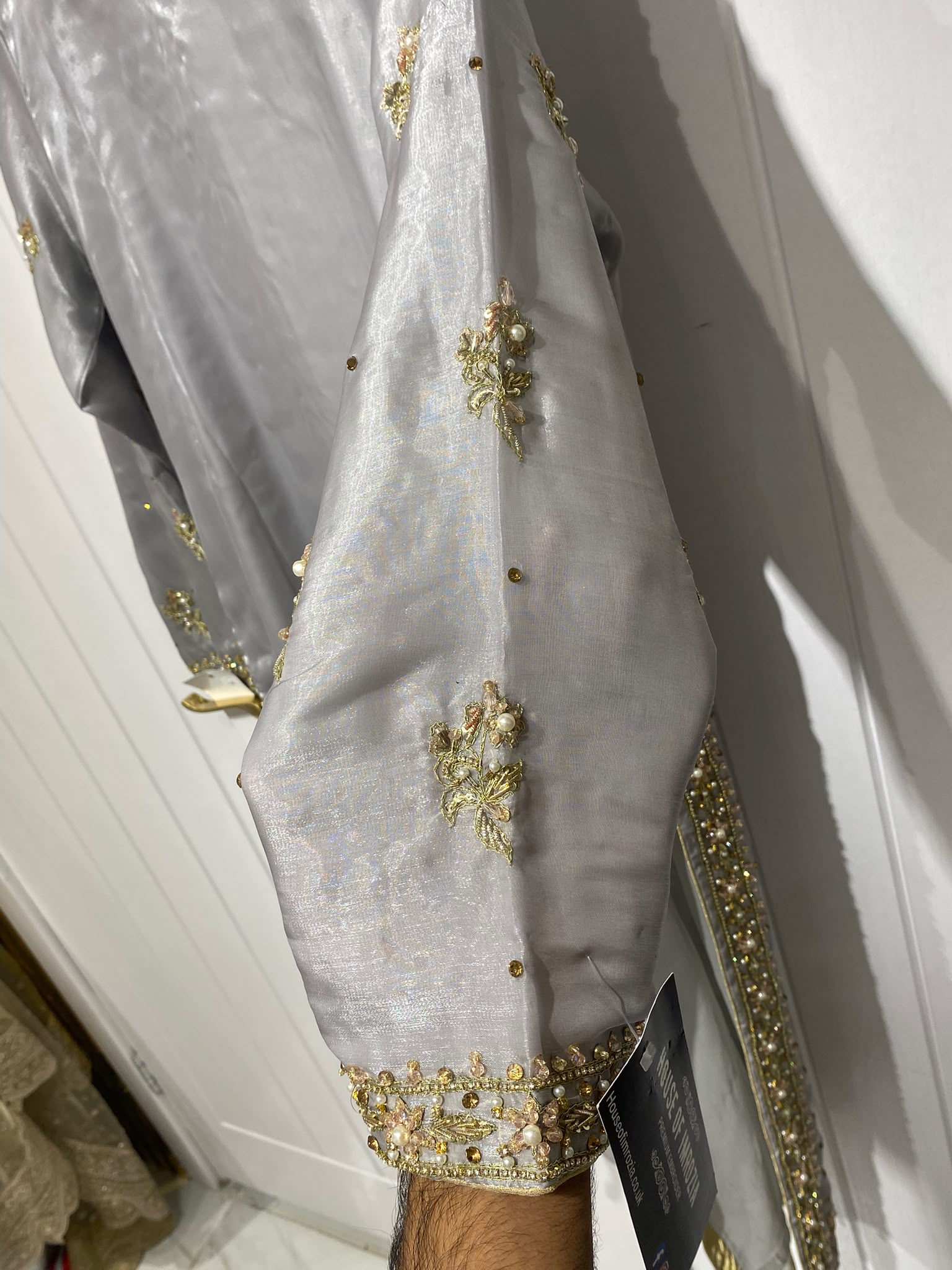 A silver grey ensemble with ornate gold-toned embroidery, decorated…
