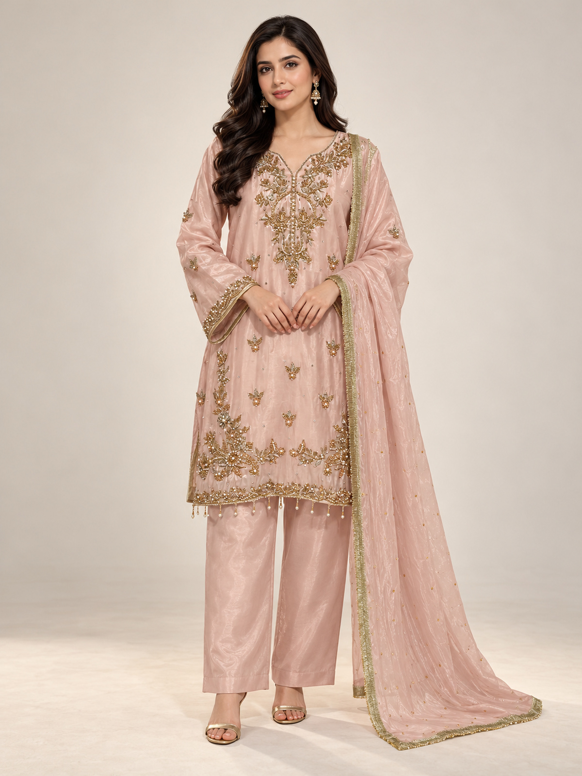 A blush pink shirt with a statement gold-toned neckline, scattered…