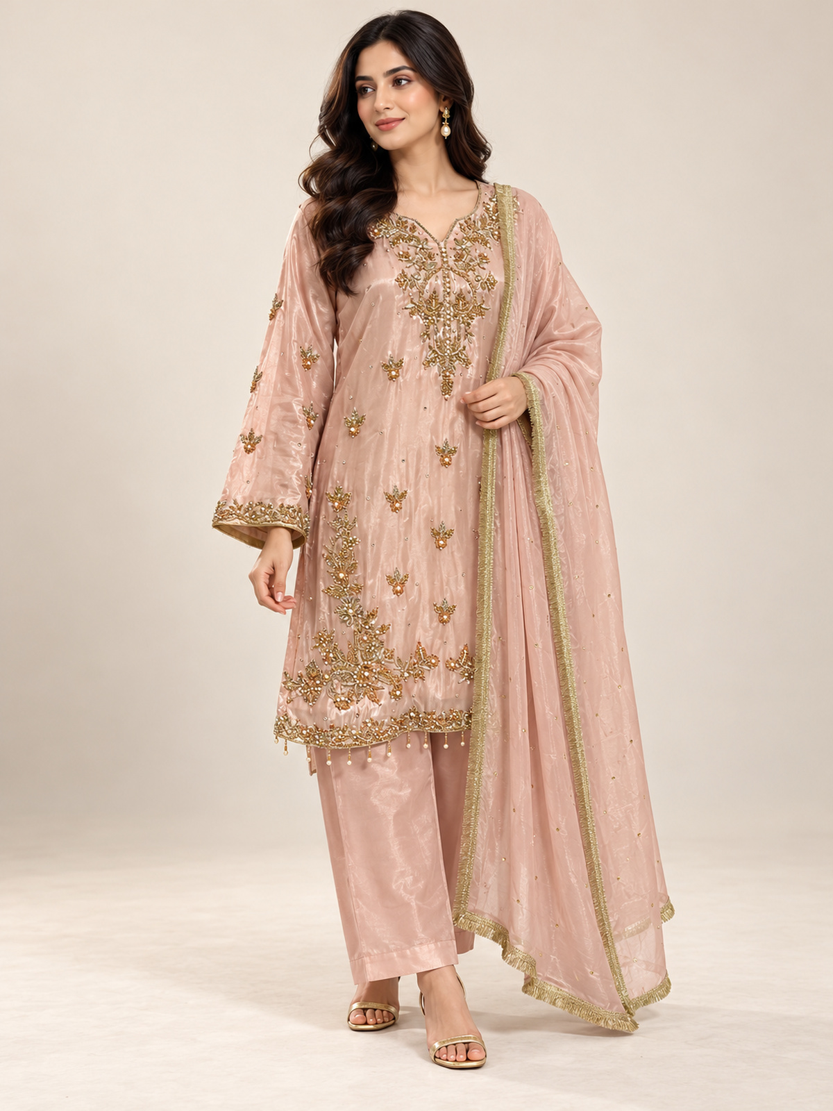 A blush pink shirt with a statement gold-toned neckline, scattered…