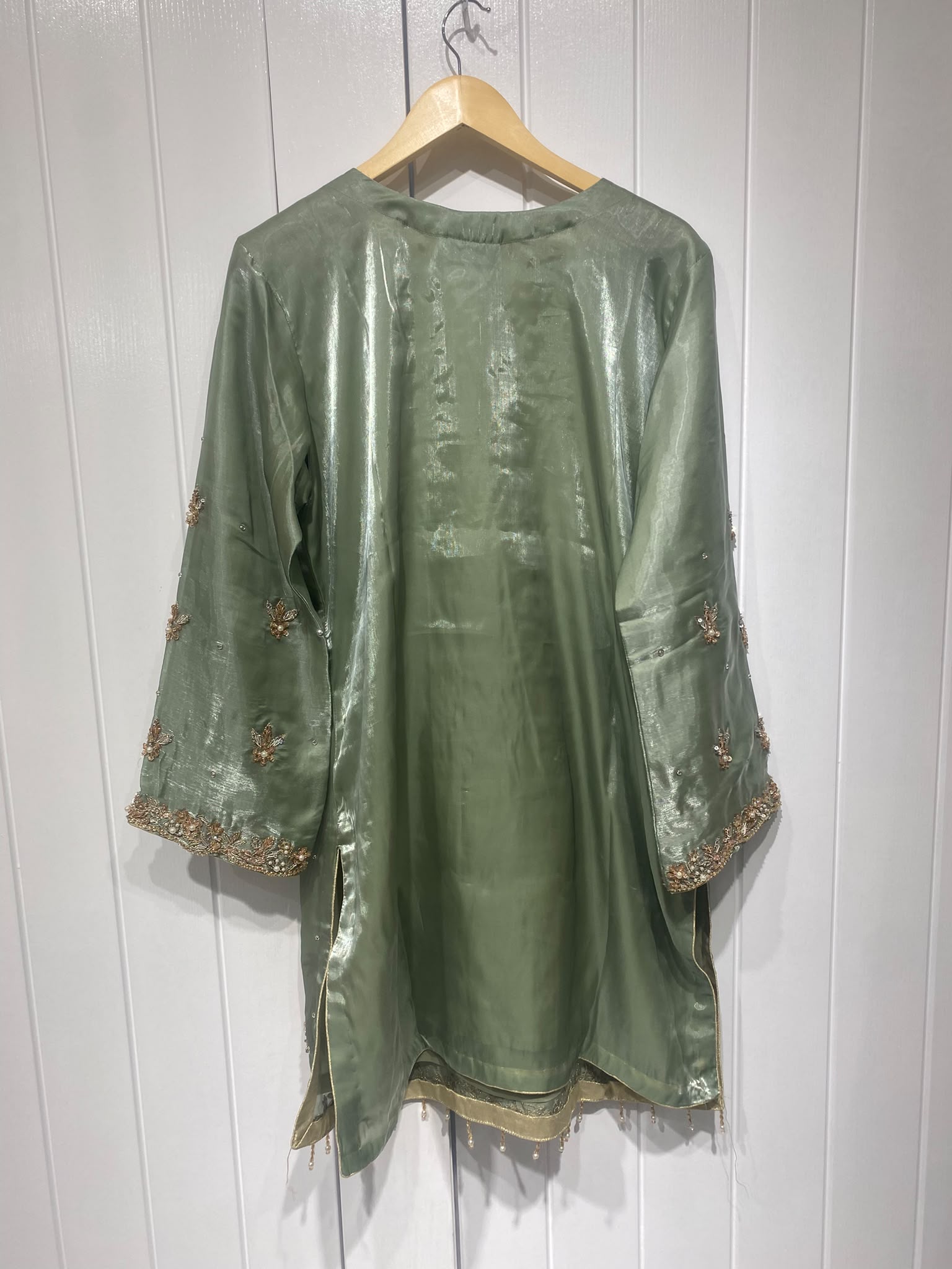 A sage green ensemble with a floral embroidered neckline, ornate…