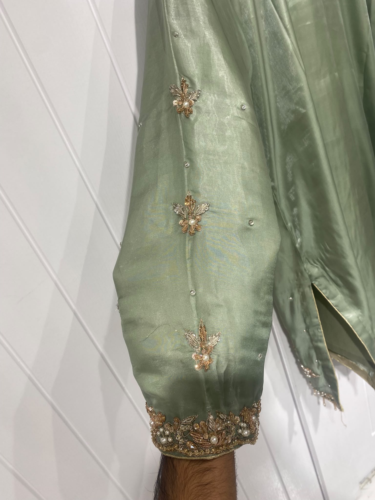 A sage green ensemble with a floral embroidered neckline, ornate…