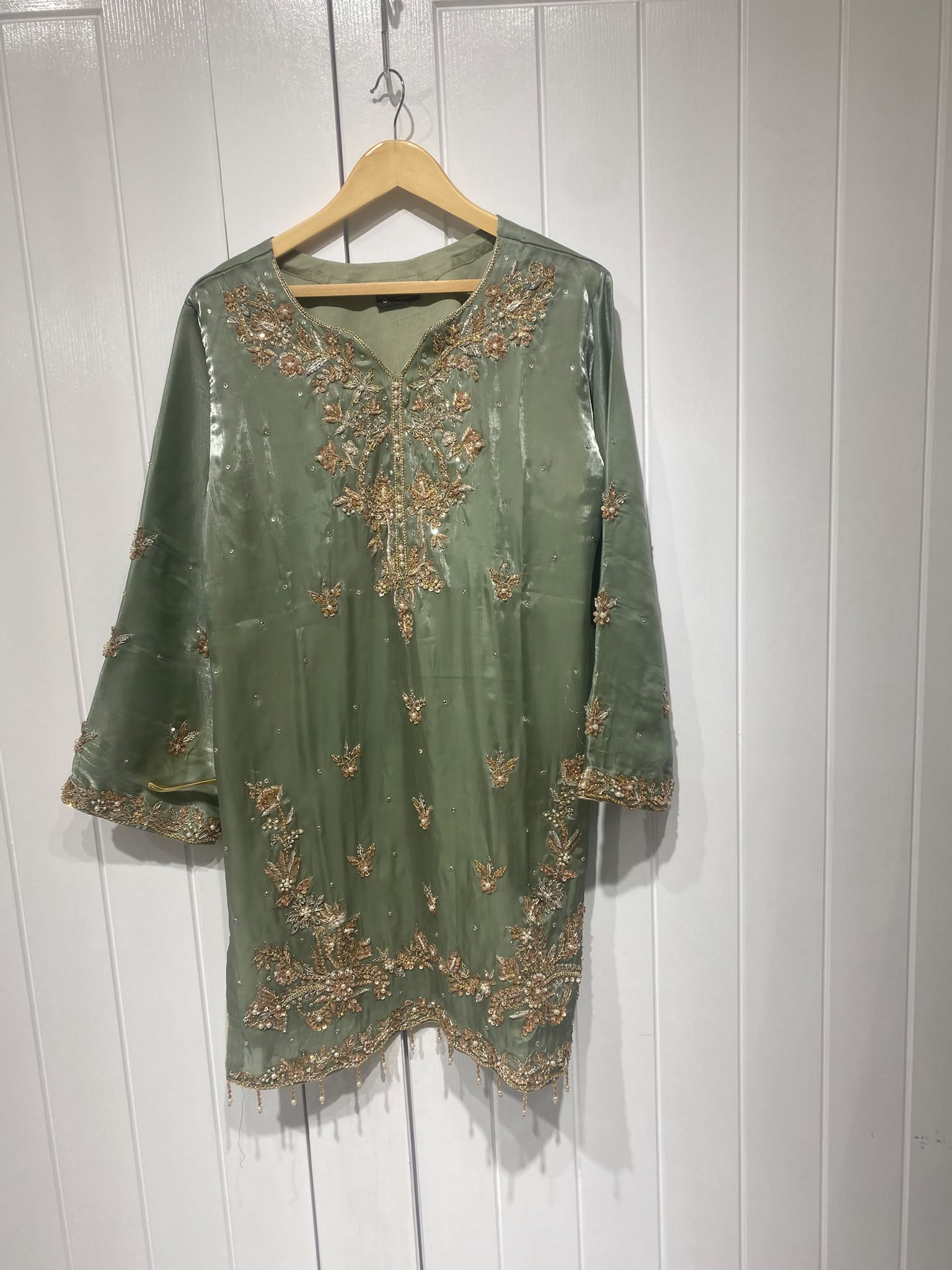 A sage green ensemble with a floral embroidered neckline, ornate…