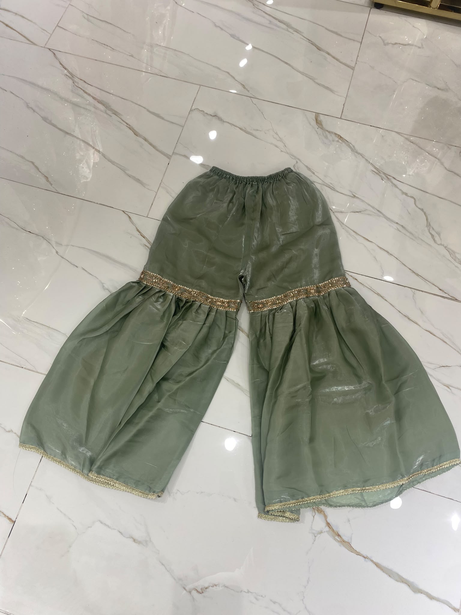 A sage green ensemble with a floral embroidered neckline, ornate…