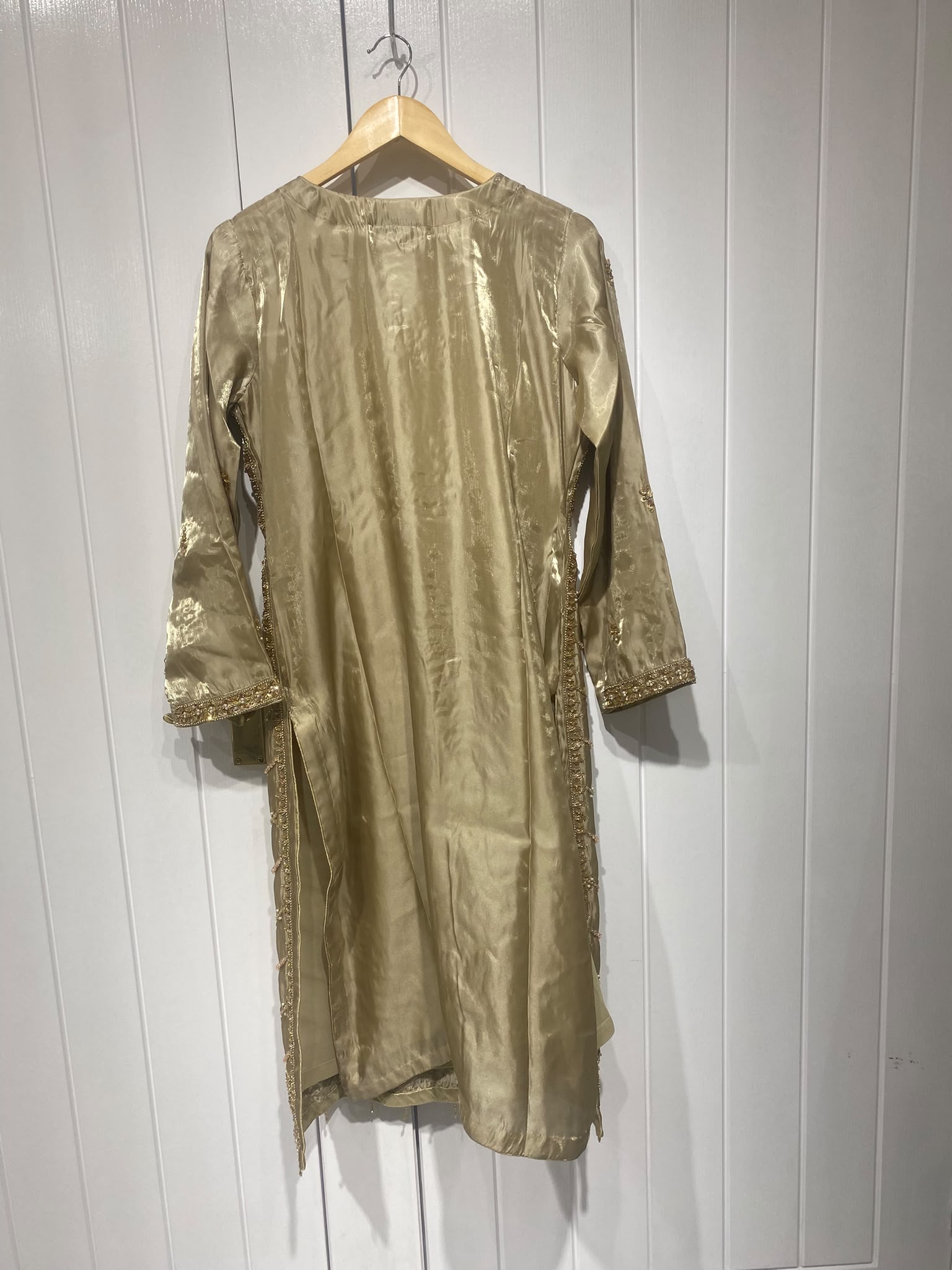 An olive gold ensemble with an elongated embroidered neckline, ornate…