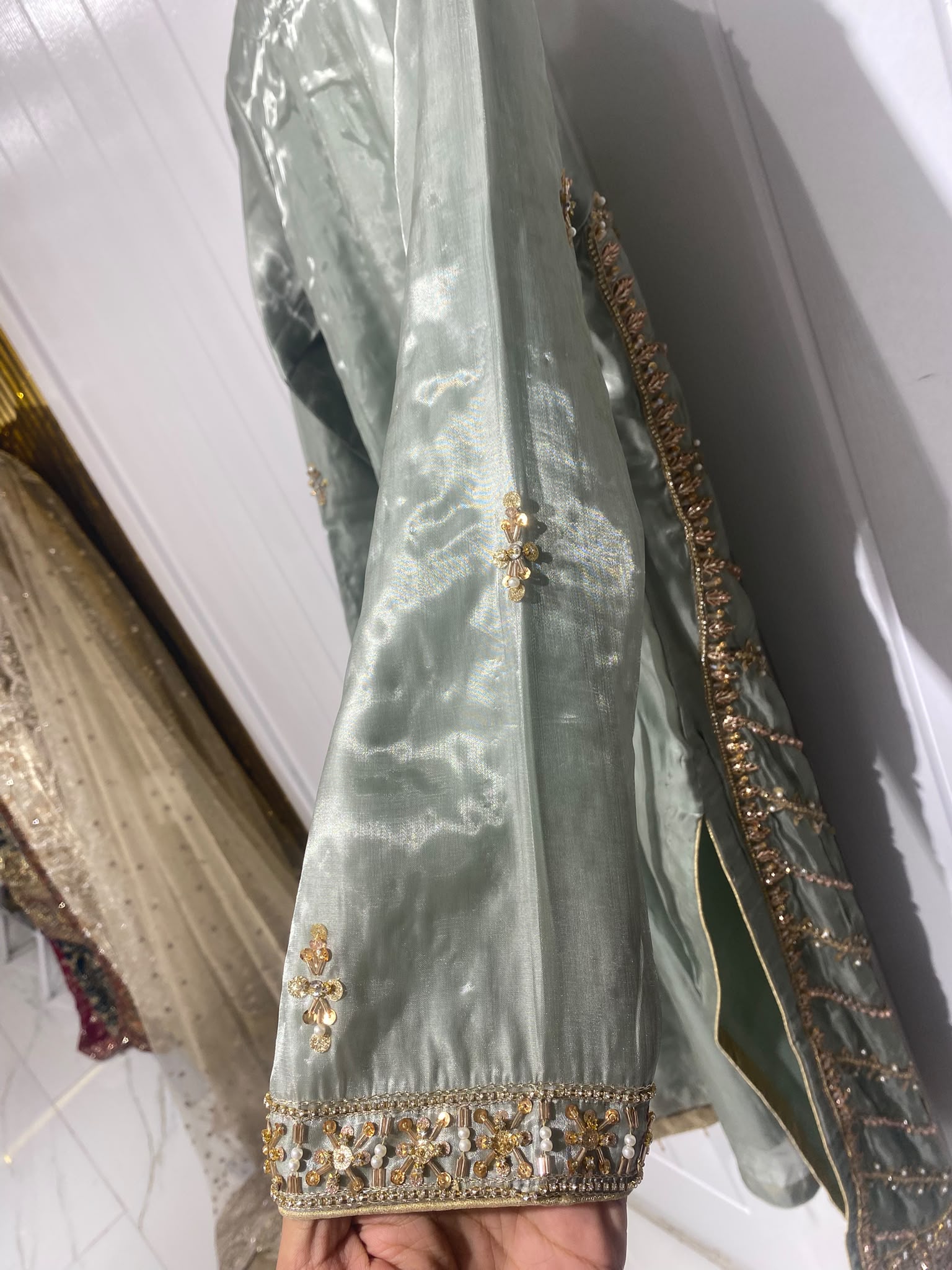 A sage grey ensemble with a long ornate neckline, floral border…