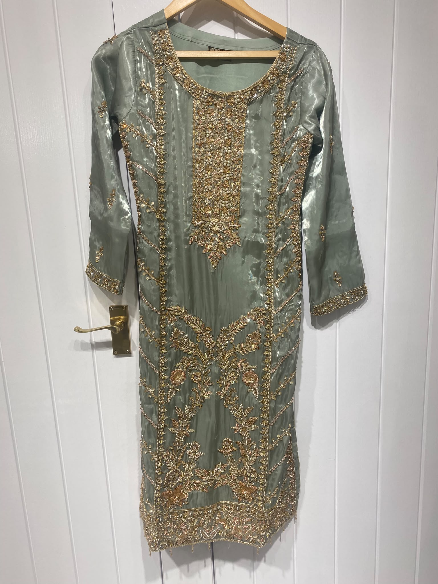 A sage grey ensemble with a long ornate neckline, floral border…