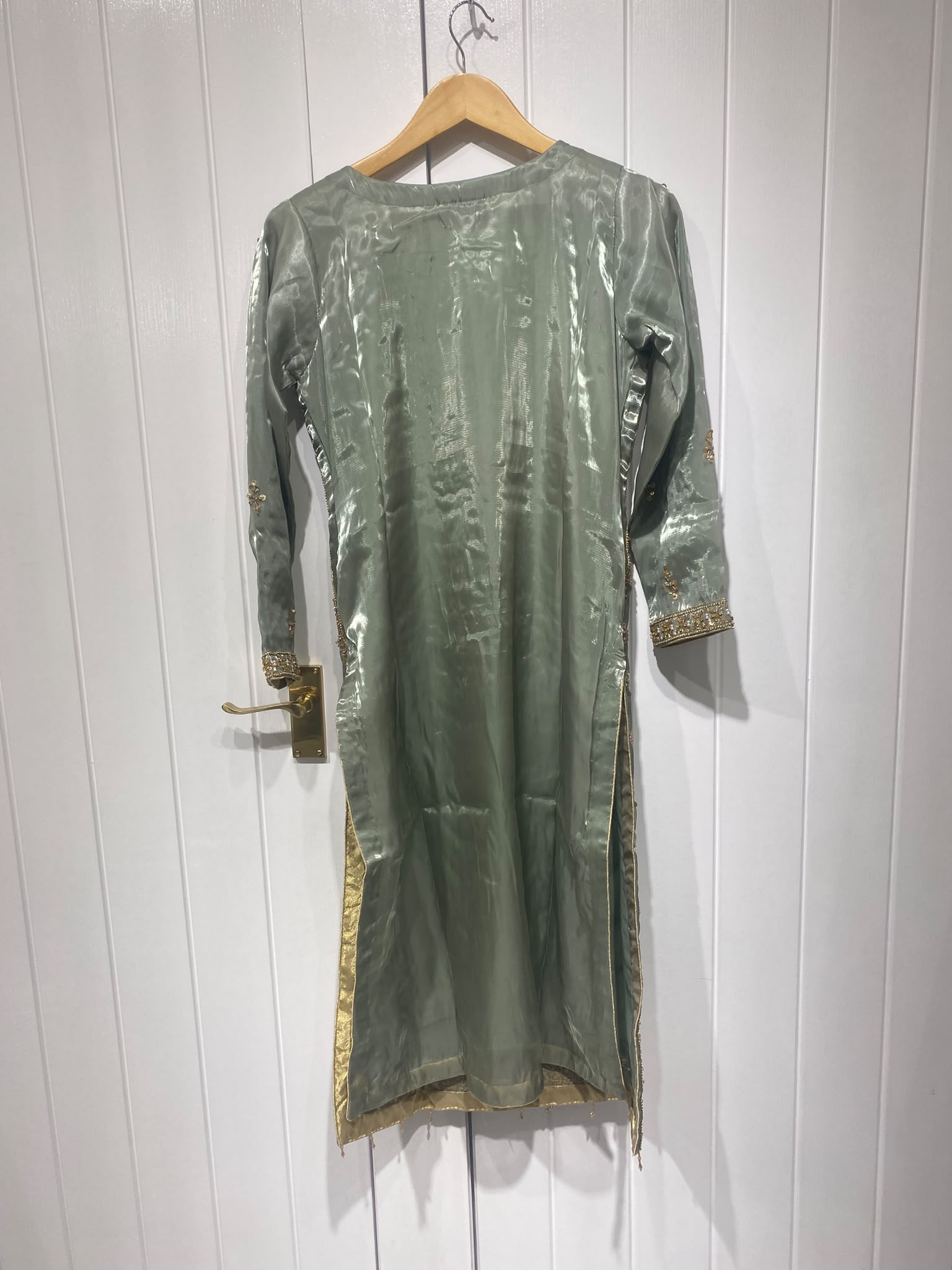 A sage grey ensemble with a long ornate neckline, floral border…