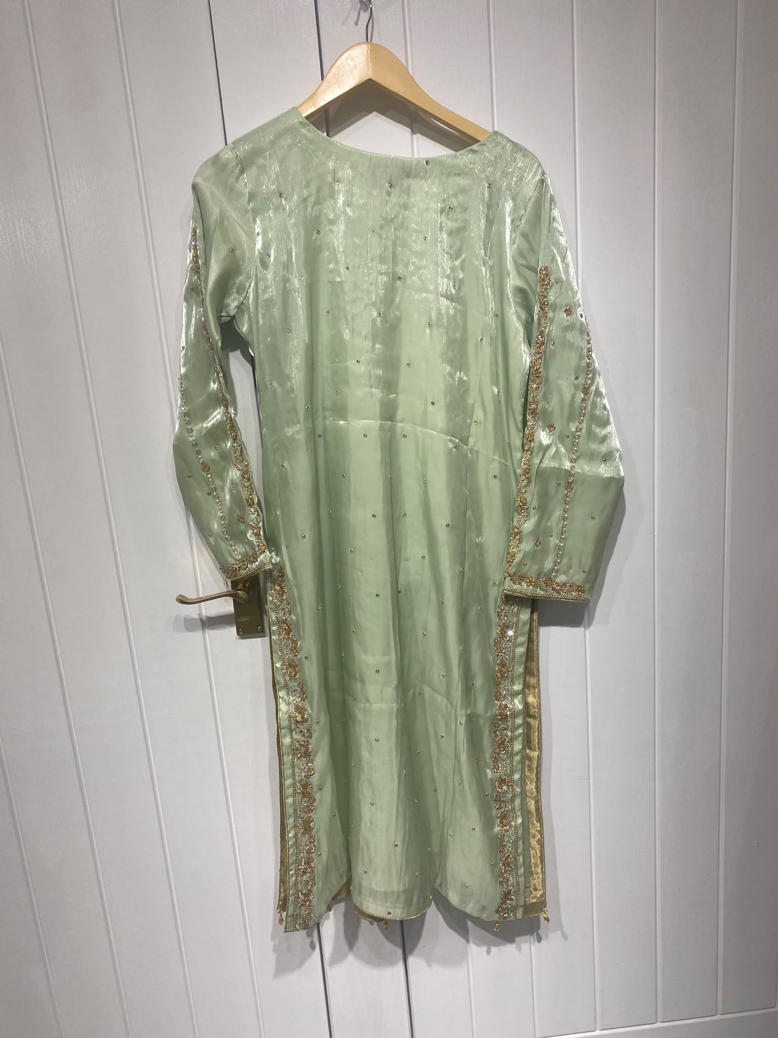 A pistachio green ensemble with a framed embroidered bib, scattered…