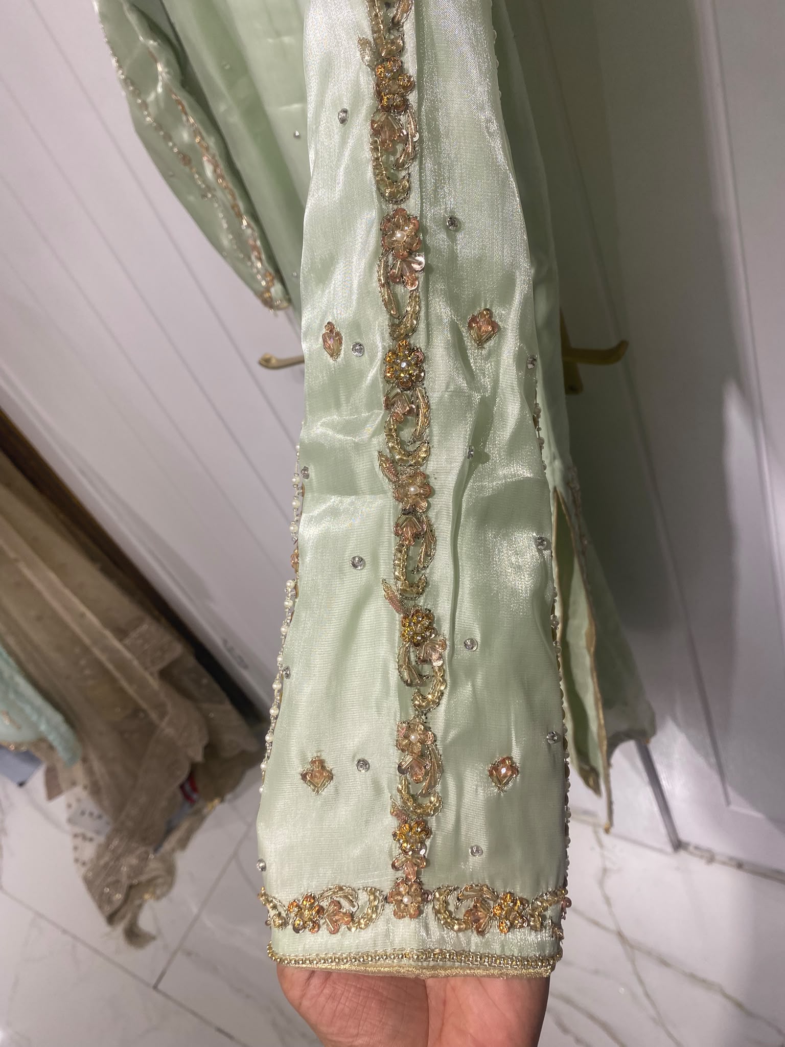 A pistachio green ensemble with a framed embroidered bib, scattered…