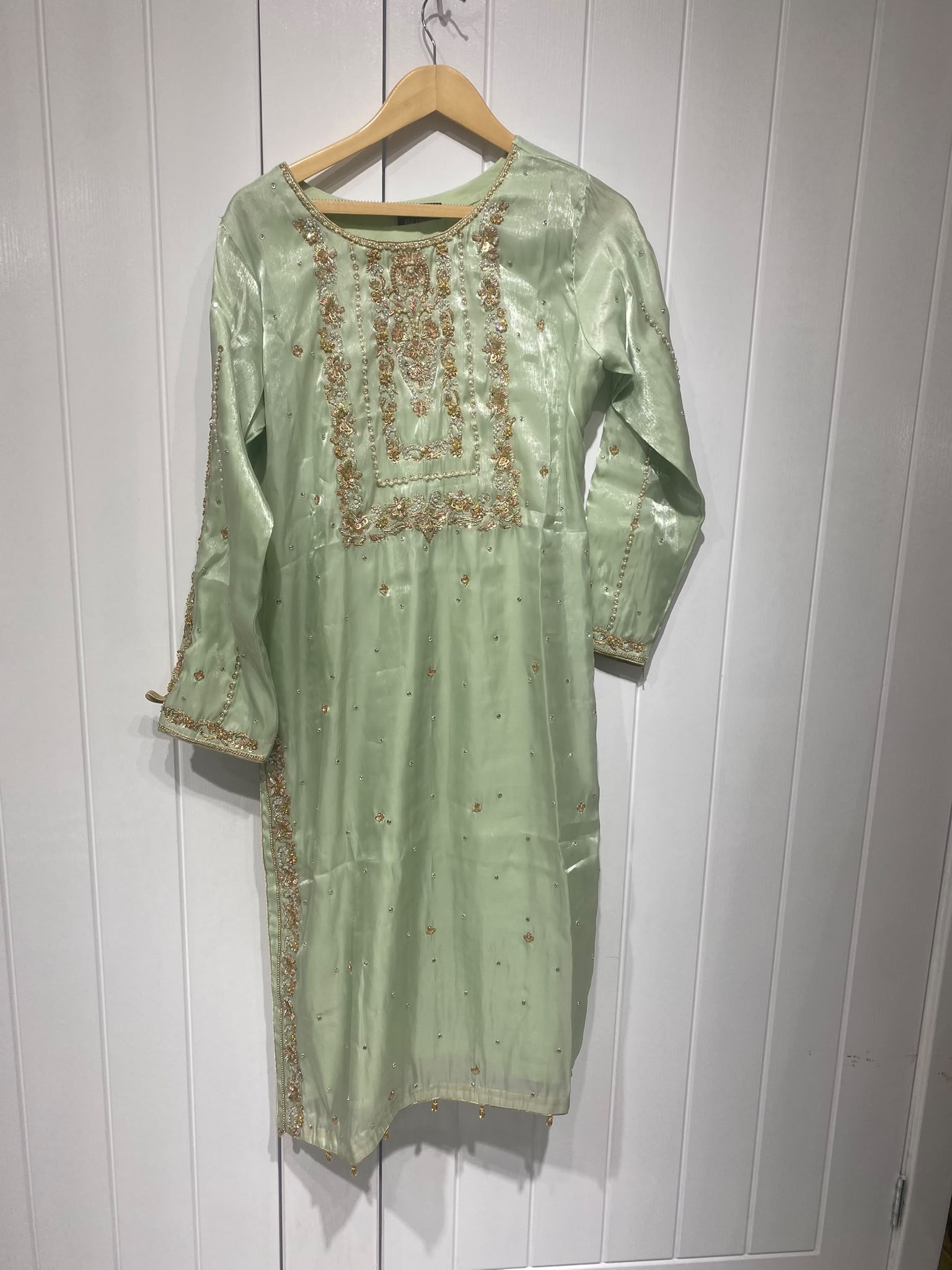 A pistachio green ensemble with a framed embroidered bib, scattered…