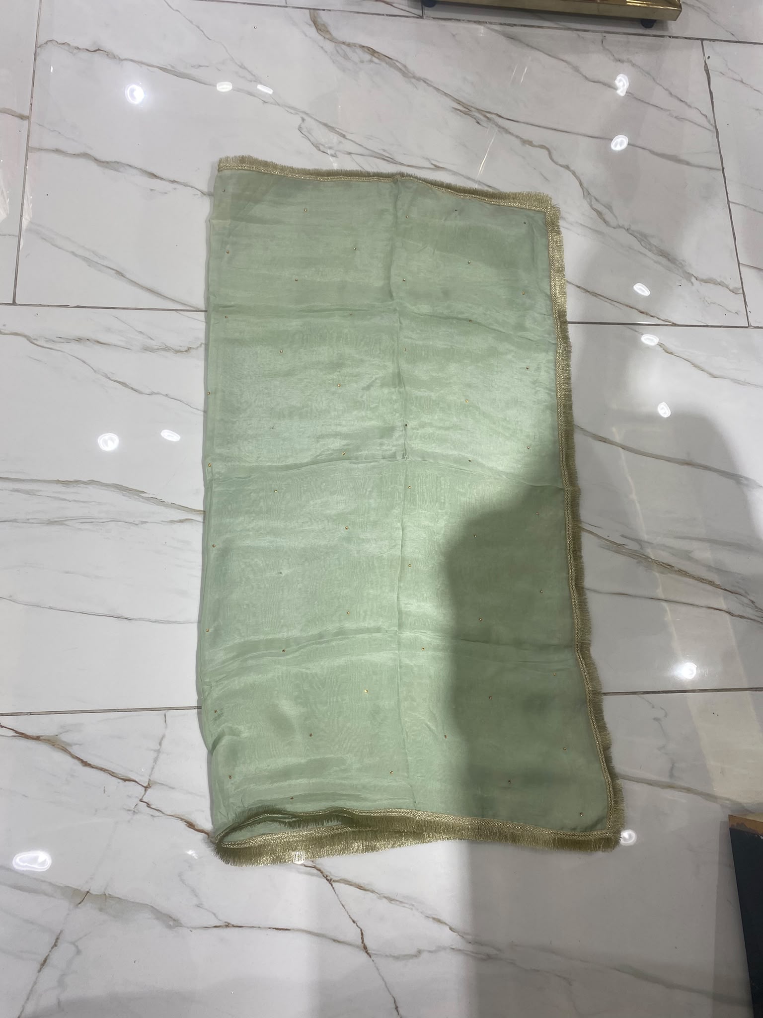 A pistachio green ensemble with a framed embroidered bib, scattered…