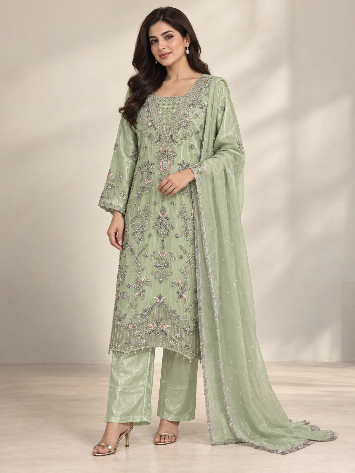 A light green ensemble with silver-toned floral embroidery, a…