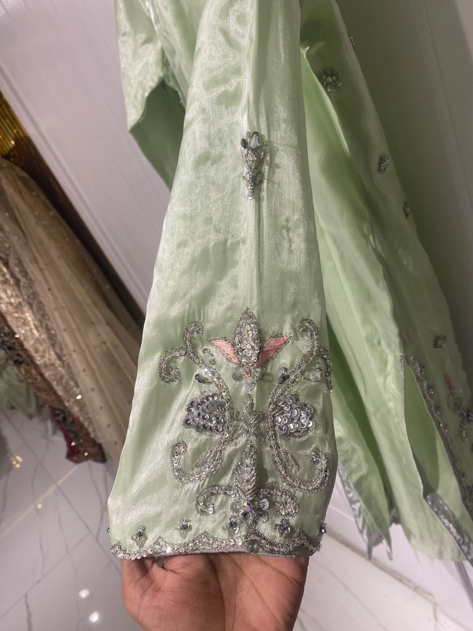 A light green ensemble with silver-toned floral embroidery, a…