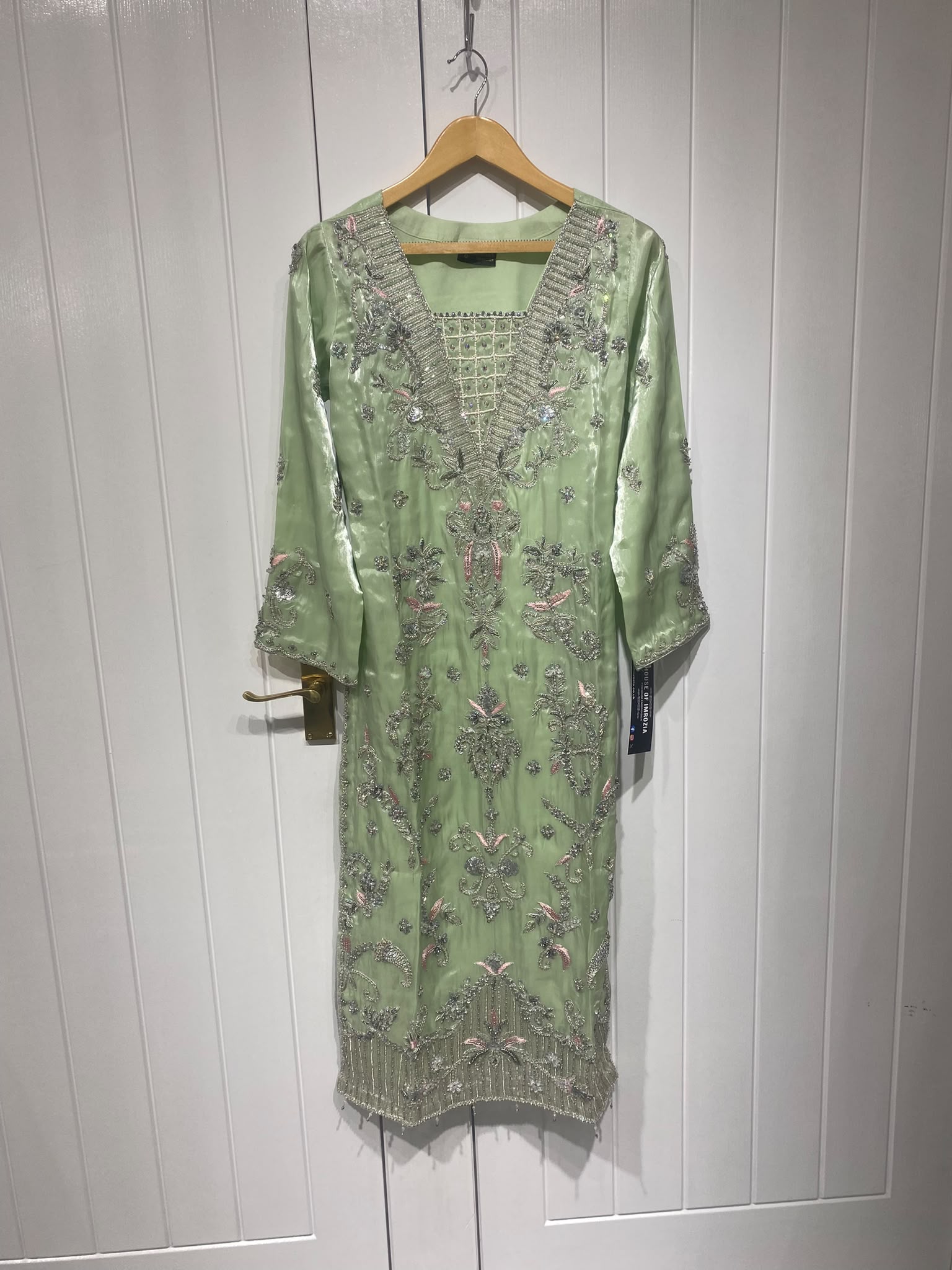A light green ensemble with silver-toned floral embroidery, a…
