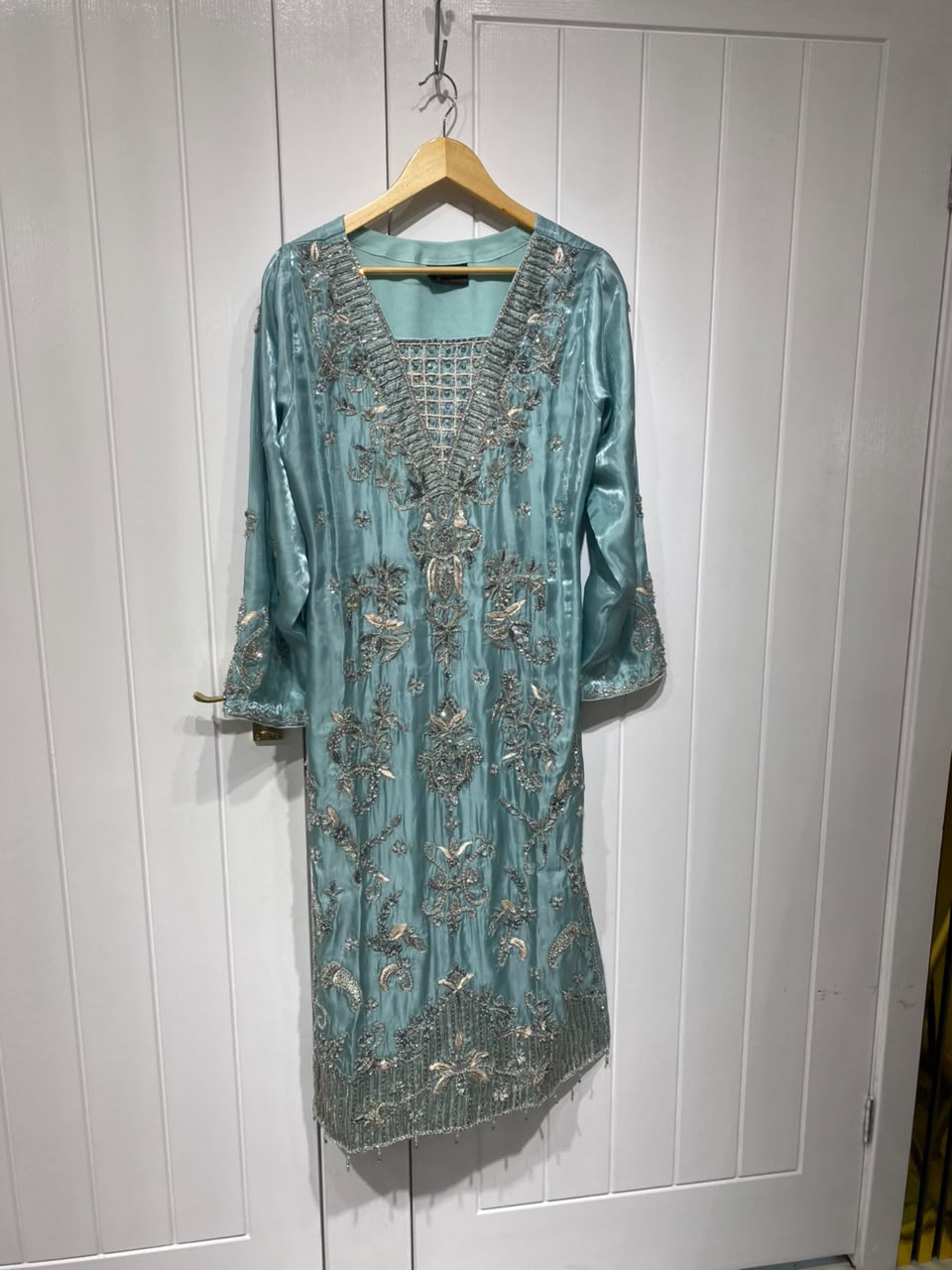 A lustrous aqua blue shirt with ornate gold-toned embroidery…