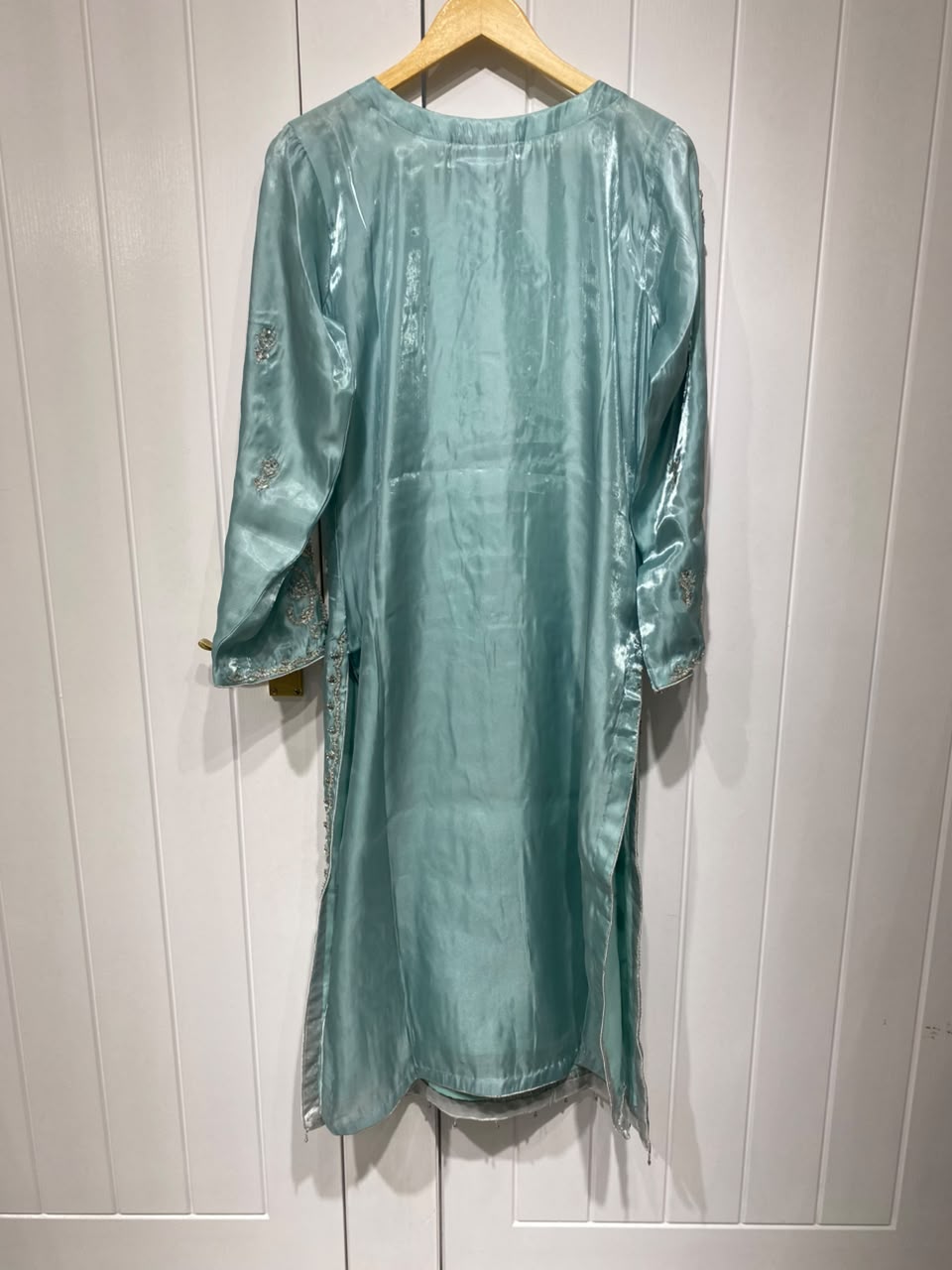 A lustrous aqua blue shirt with ornate gold-toned embroidery…