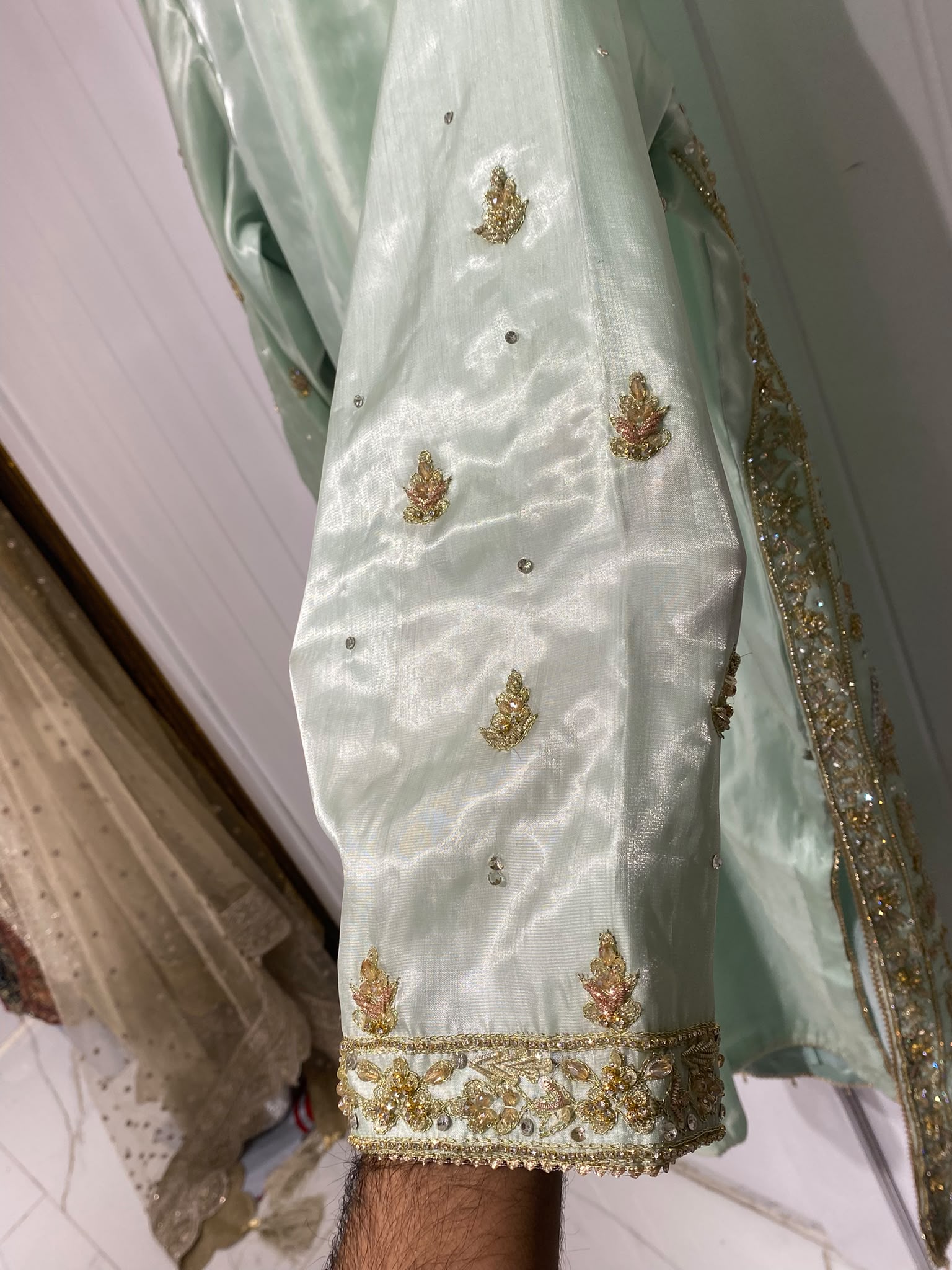 A pale mint ensemble with a decorative neckline, long embroidered…