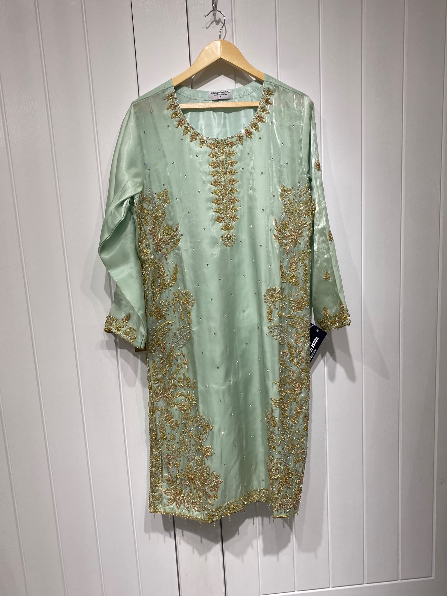 A pale mint ensemble with a decorative neckline, long embroidered…