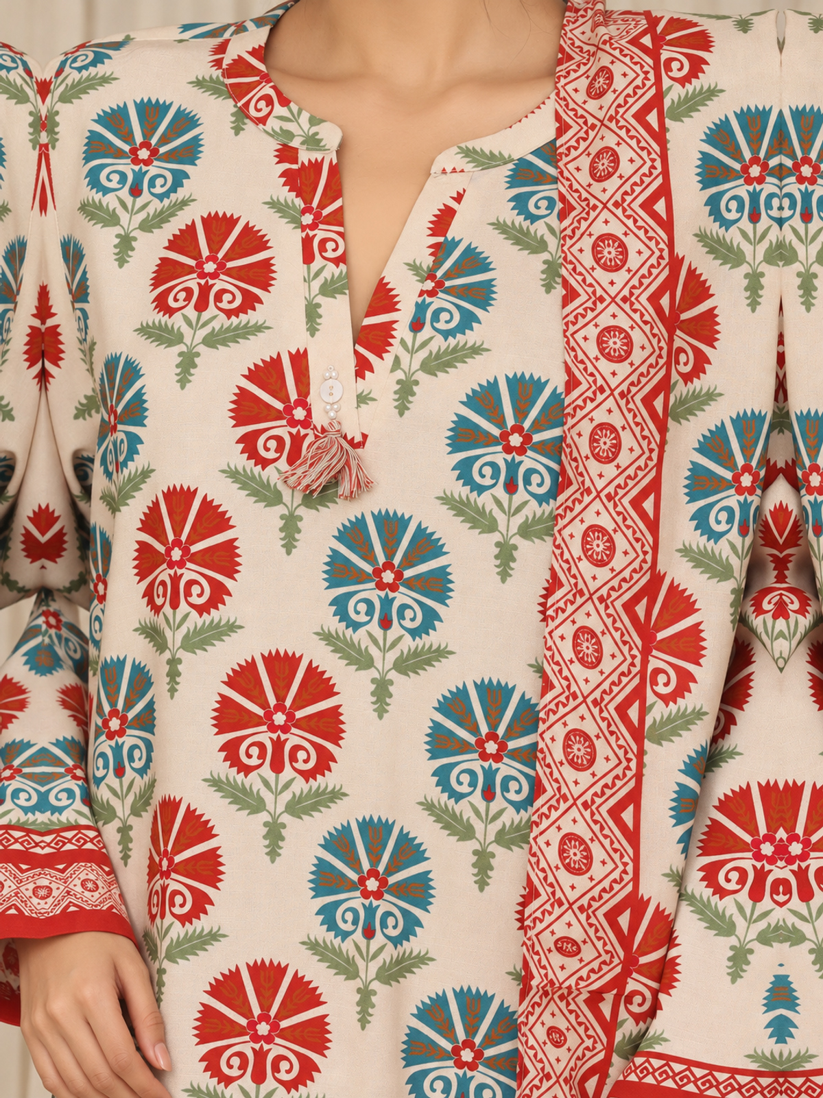 An ivory shirt with red and green ornamental motifs, red patterned…