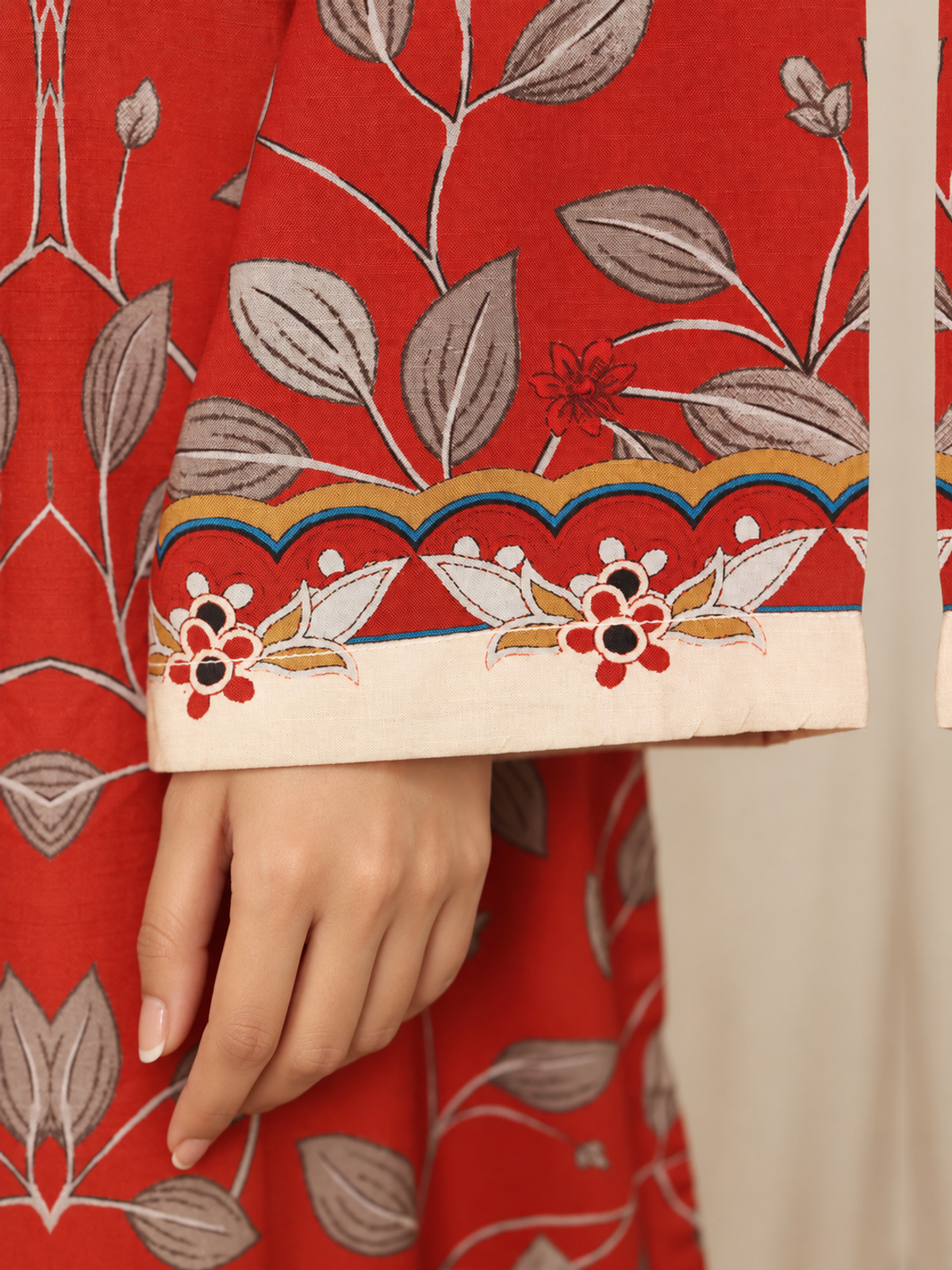 A red shirt covered with pale botanical motifs, teamed with cream…