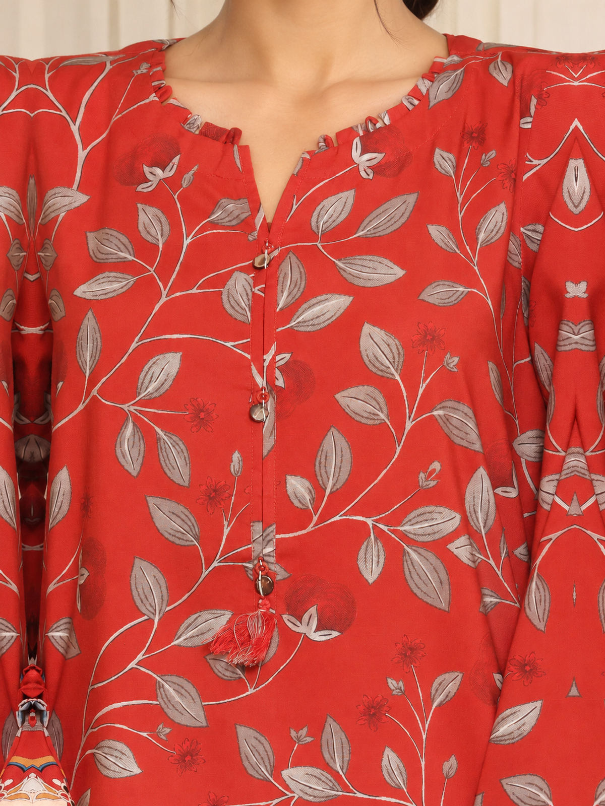 A red shirt covered with pale botanical motifs, teamed with cream…