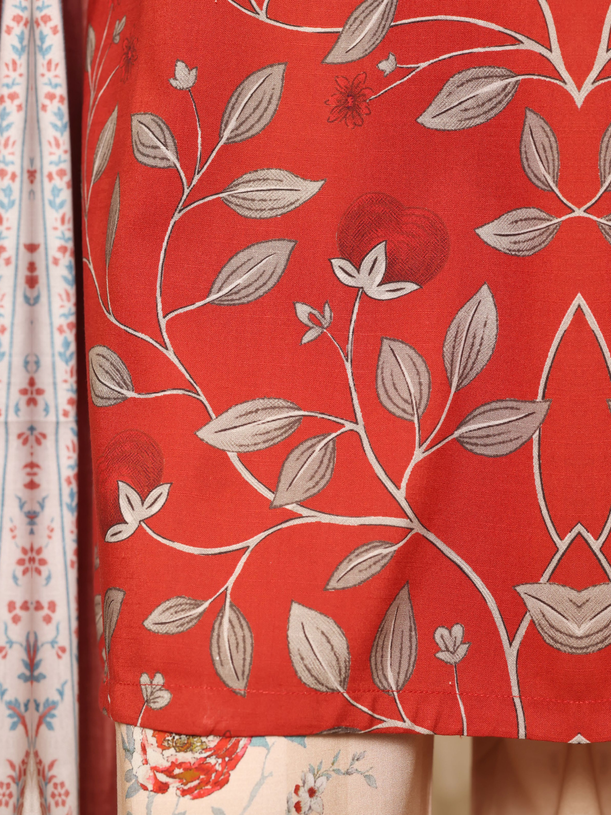 A red shirt covered with pale botanical motifs, teamed with cream…