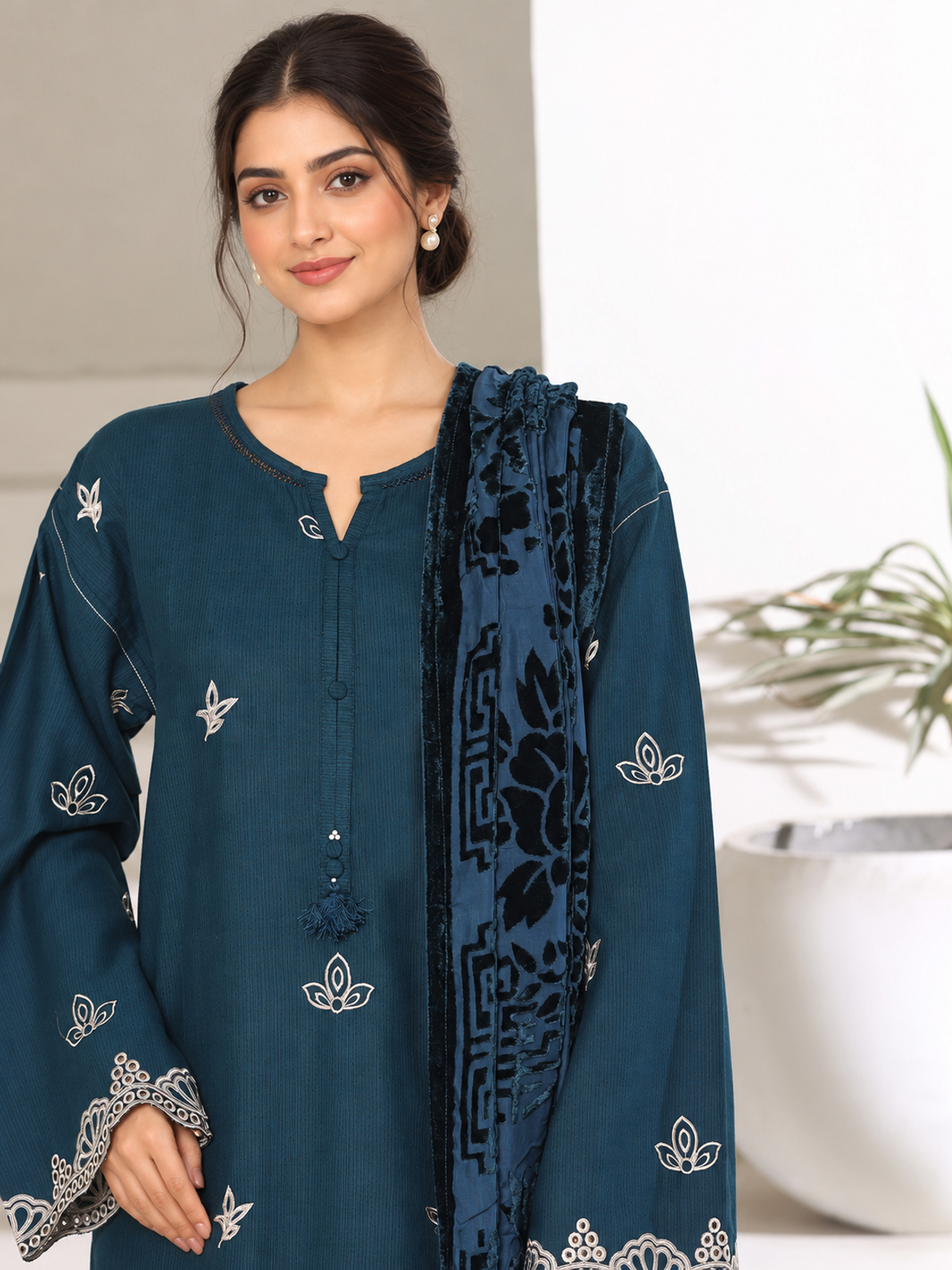 A deep-teal ensemble with contrasting pale embroidery, matching…