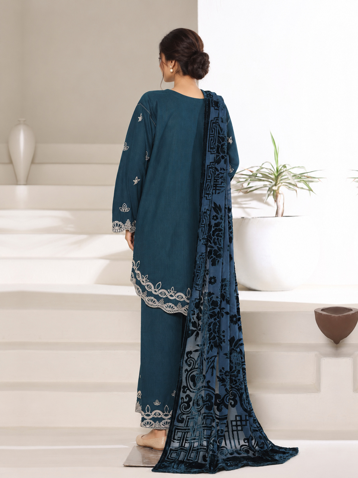 A deep-teal ensemble with contrasting pale embroidery, matching…