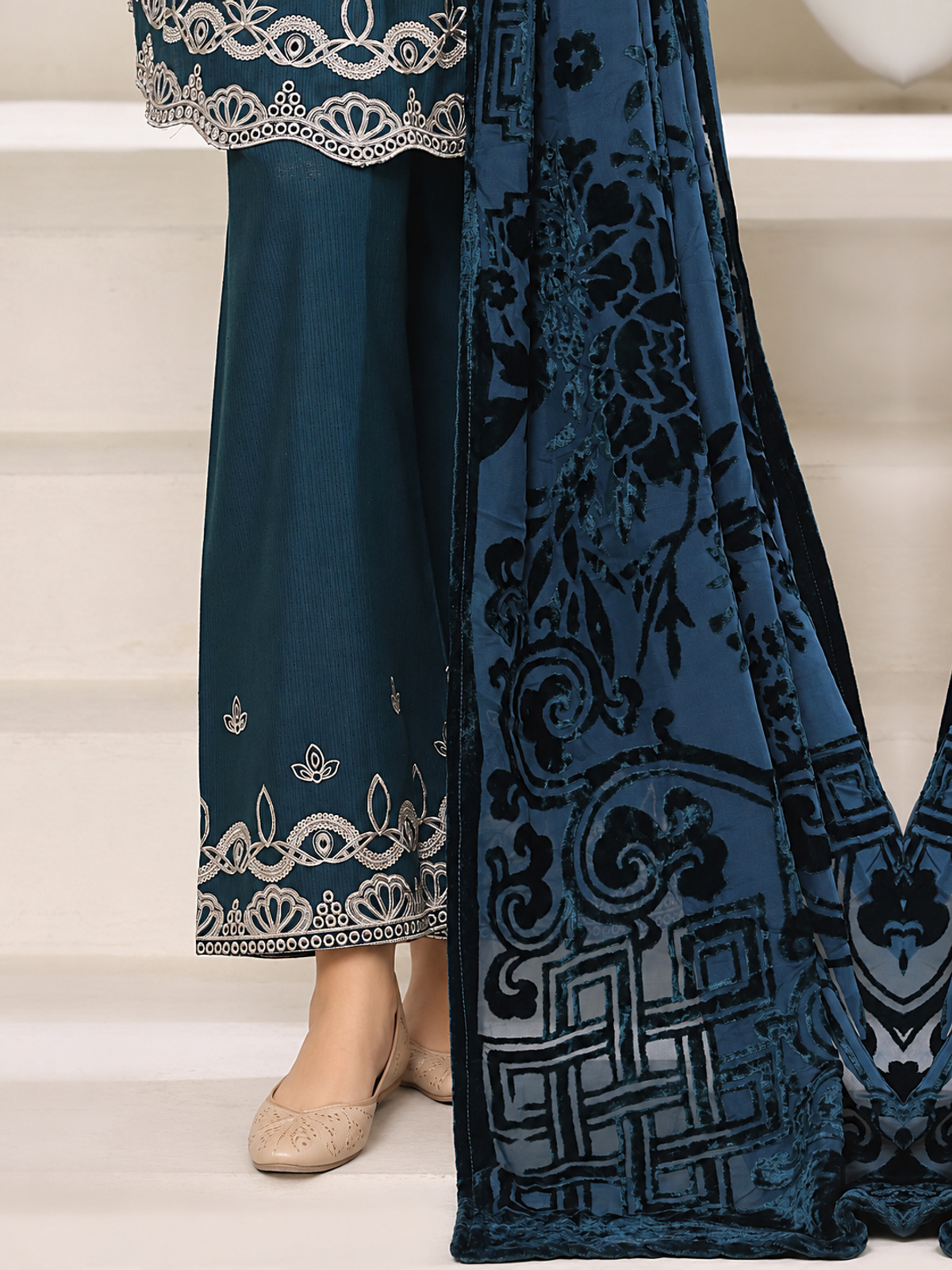 A deep-teal ensemble with contrasting pale embroidery, matching…