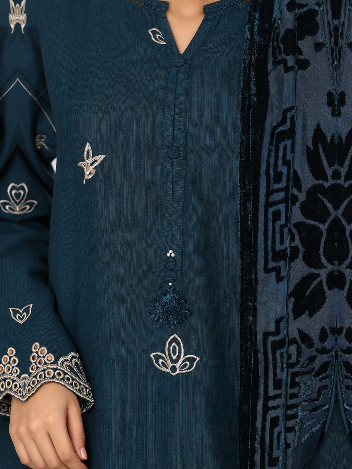 A deep-teal ensemble with contrasting pale embroidery, matching…