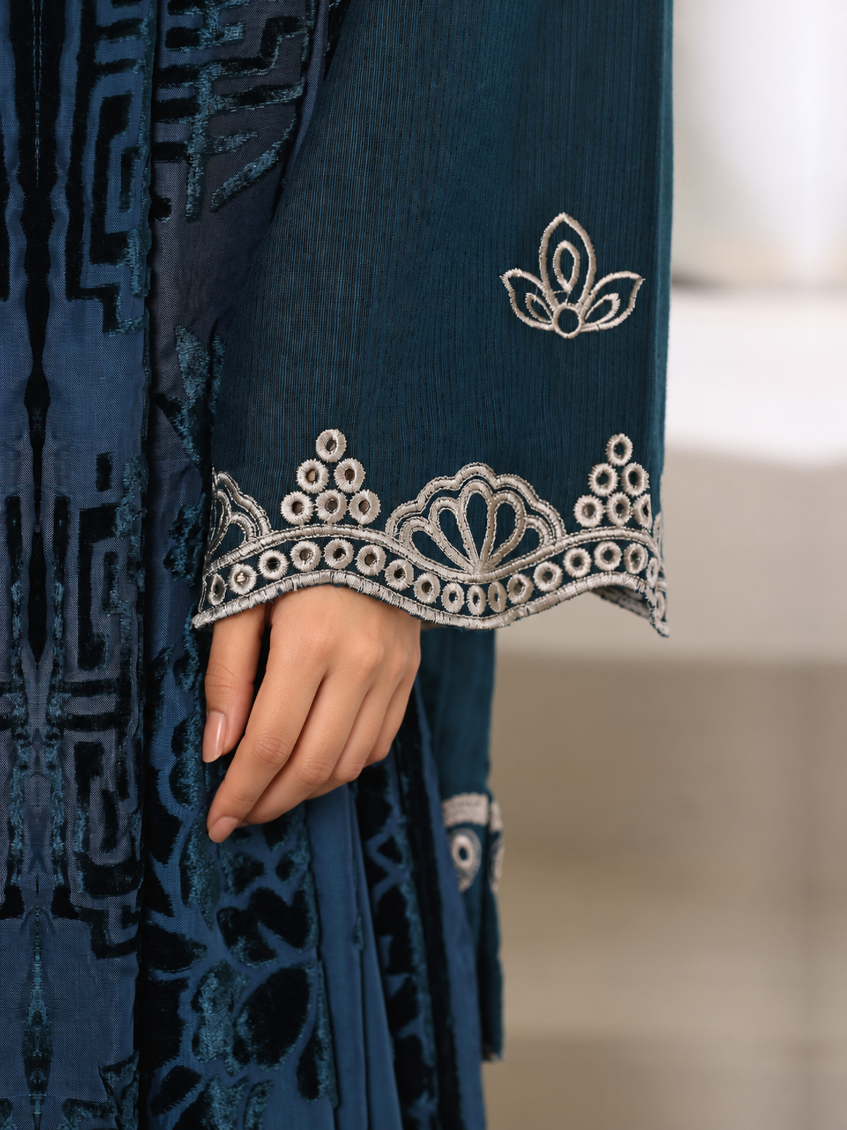 A deep-teal ensemble with contrasting pale embroidery, matching…