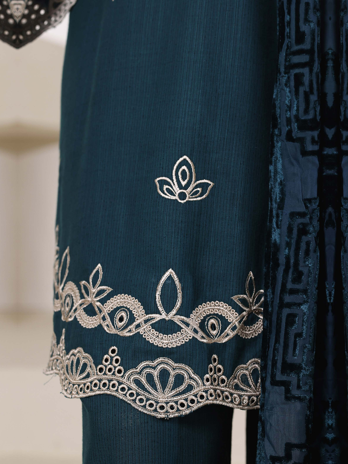 A deep-teal ensemble with contrasting pale embroidery, matching…